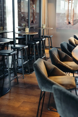 Integrated wine storage with high seating in restaurant bar, combining product display and guest experience.