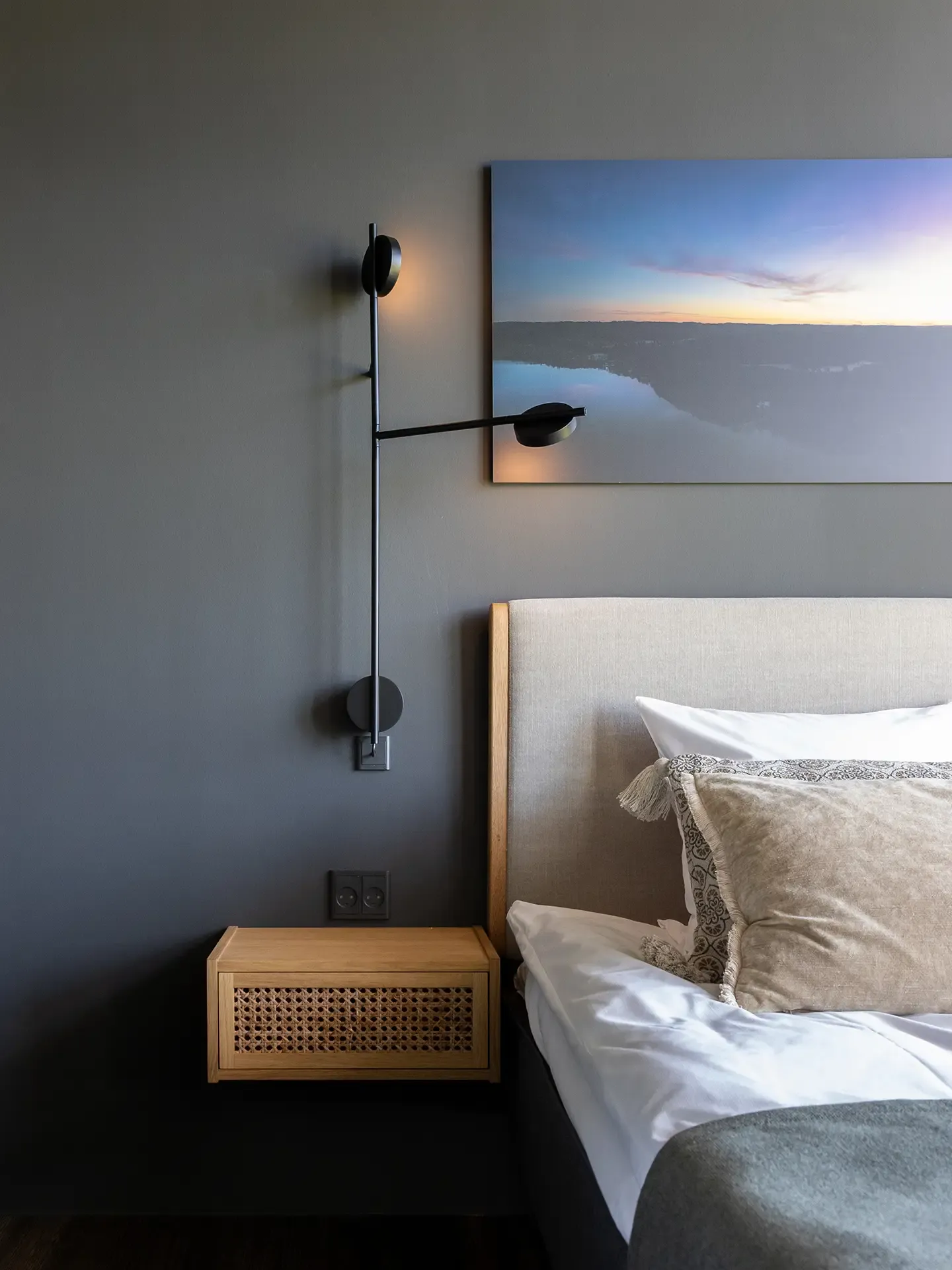 Luxury private bed room with dark grey wall, upholstered headboard and black metal wall lamp — sophisticated balance between comfort and modern design.