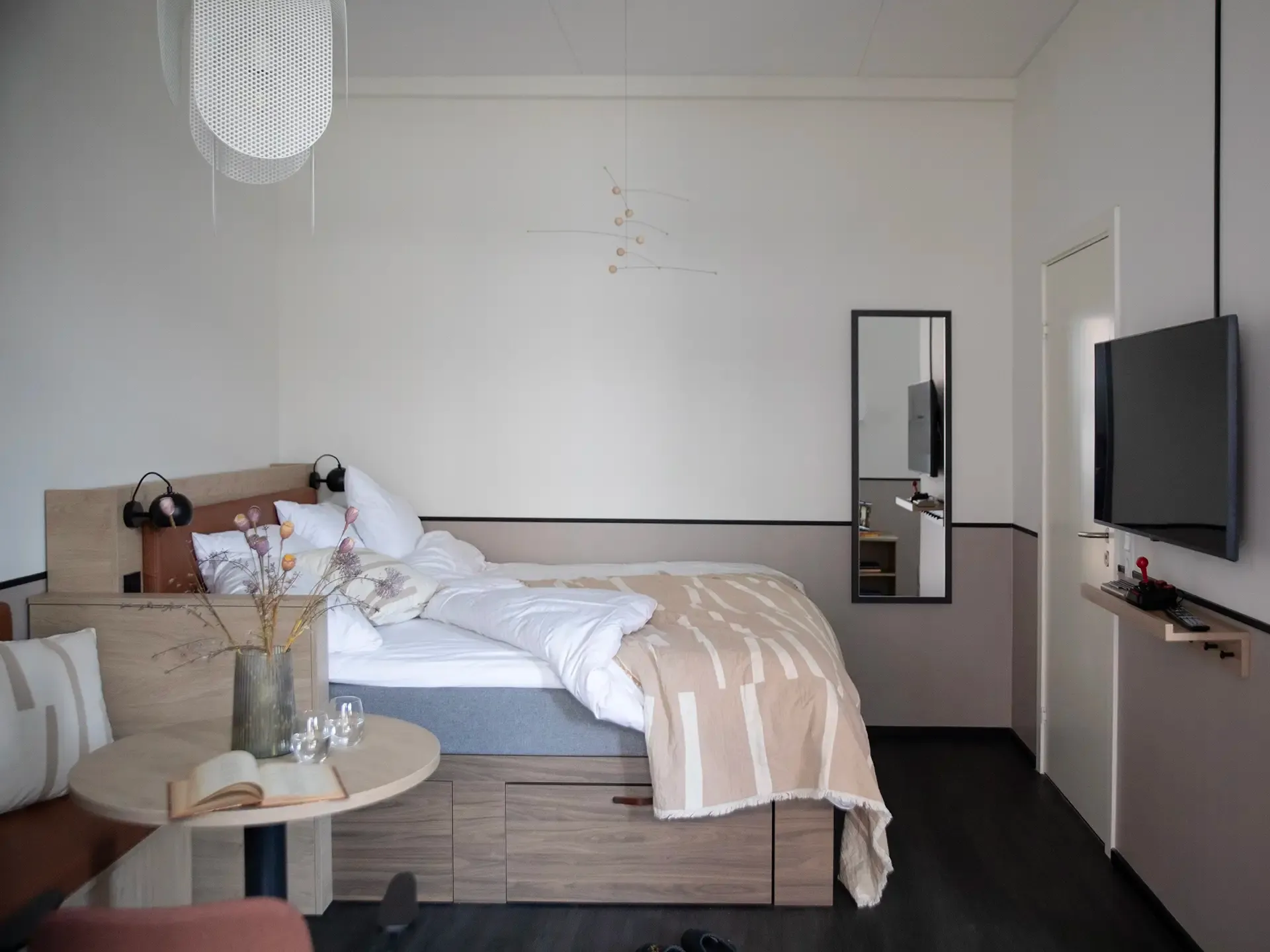 Compact hotel studio with custom-made bed, demonstrating space-efficient design solutions ideal for boutique and urban hotels.