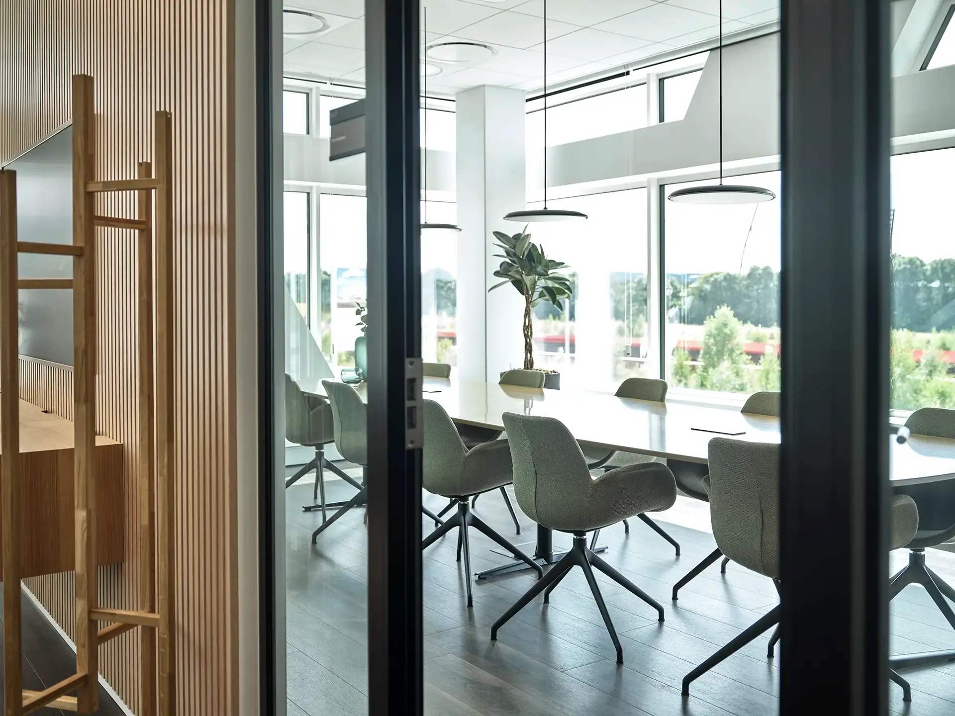 Conference room with green chairs and glass doors, providing a professional workspace with natural light and privacy.