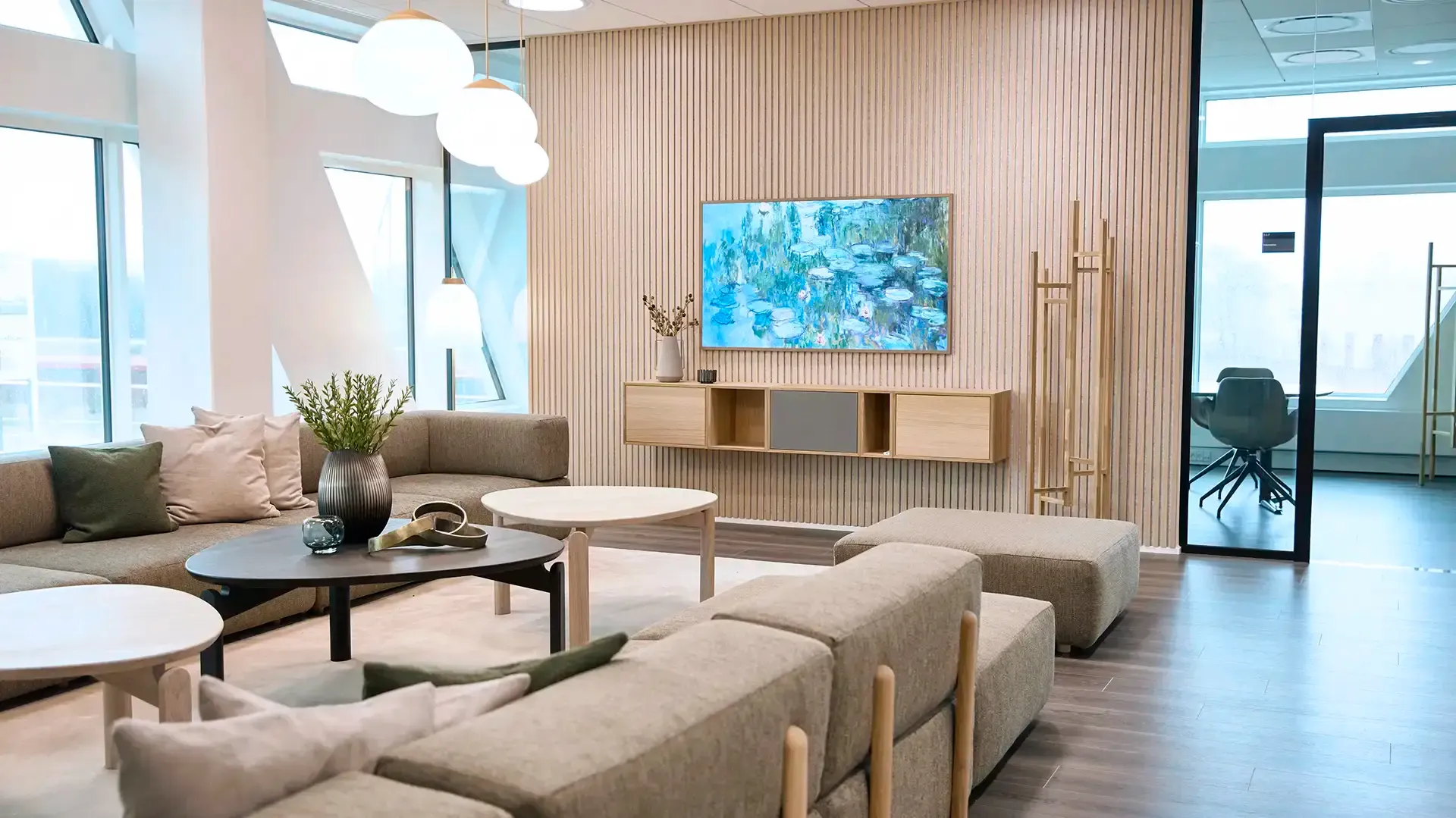 Corporate lounge with large windows, natural light and wooden details — Nordic office design promoting openness and collaboration.