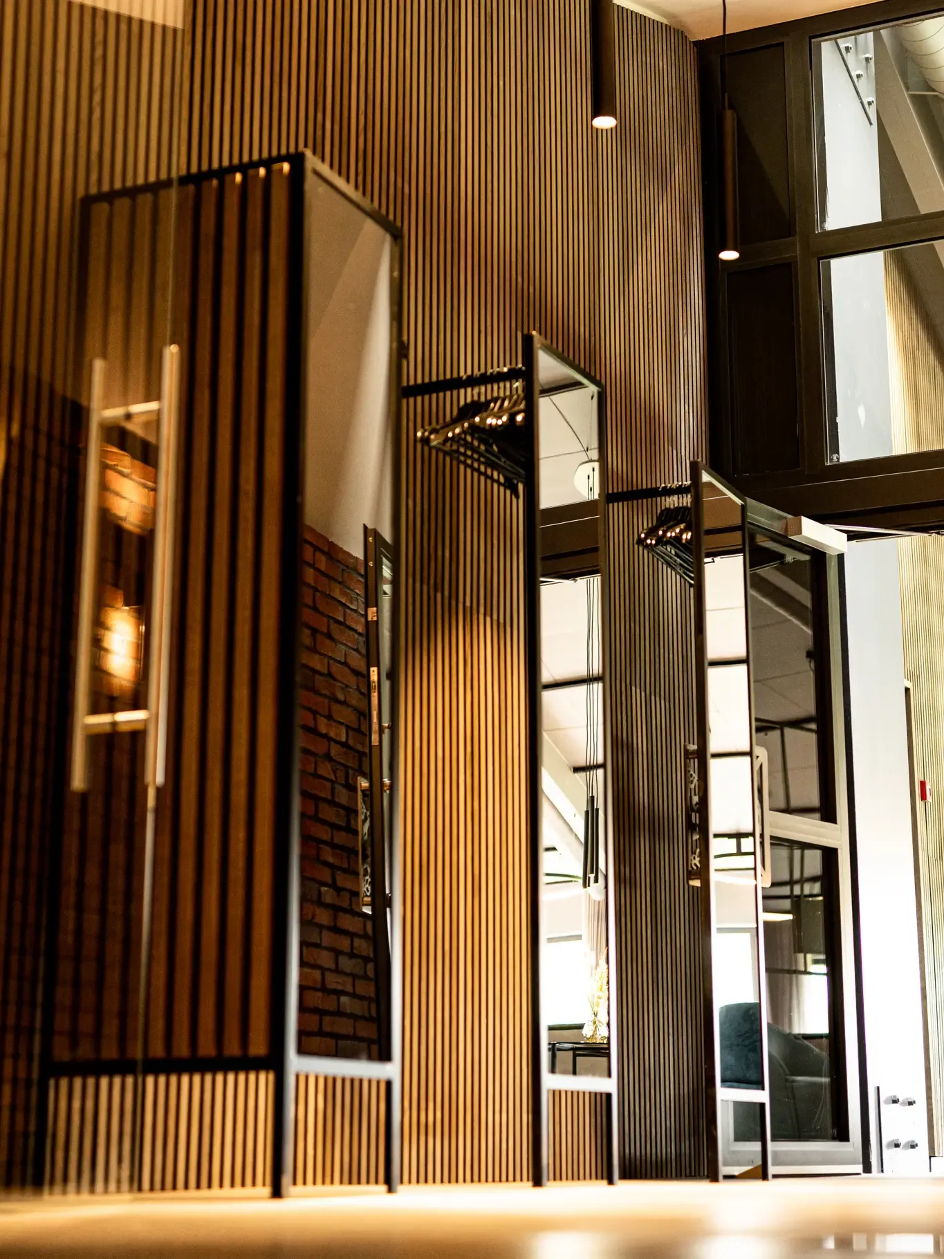 Custom made wardrobe with mirrors and black metal frame in front of acoustic oak panels.