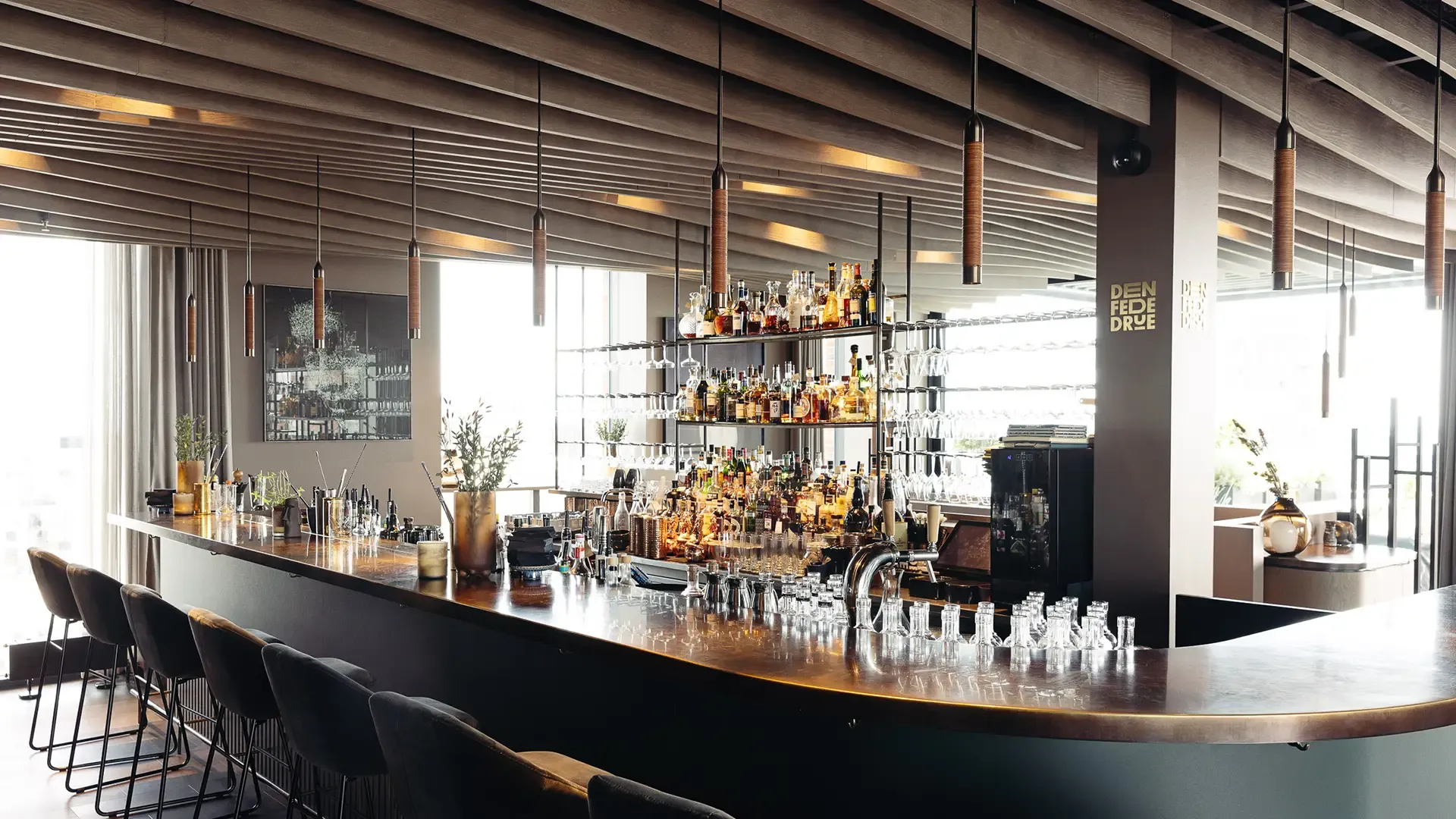 Custom-built bar for Den Fede Drue with integrated storage and guest seating, designed for efficient service and visual impact.