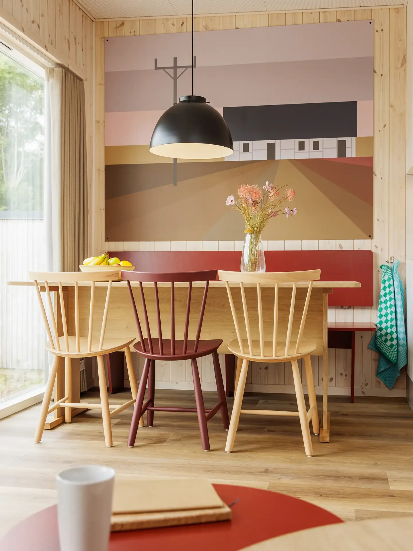 Dining area with integrated bench seating and graphic wall feature in a resort cottage at Nordborg Resort.