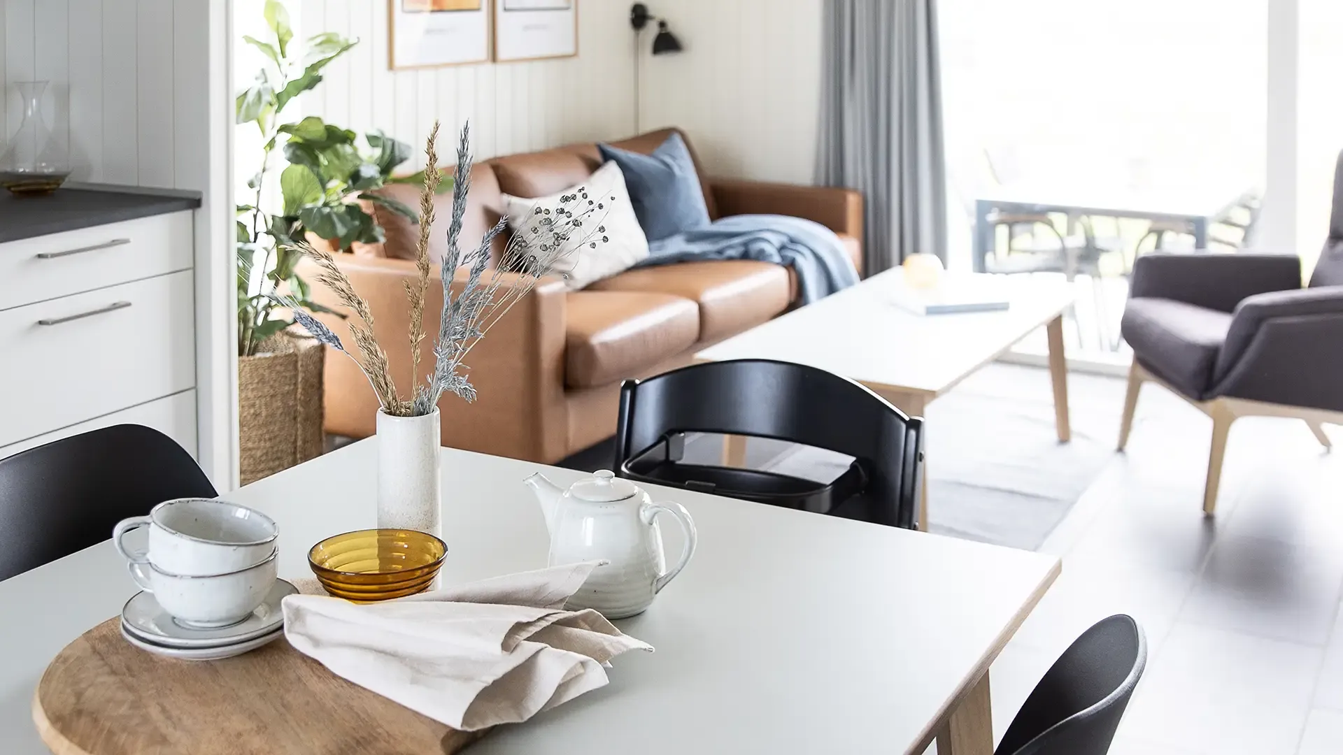 Open-plan holiday home interior with dining and living area, styled with Nordic design simplicity.