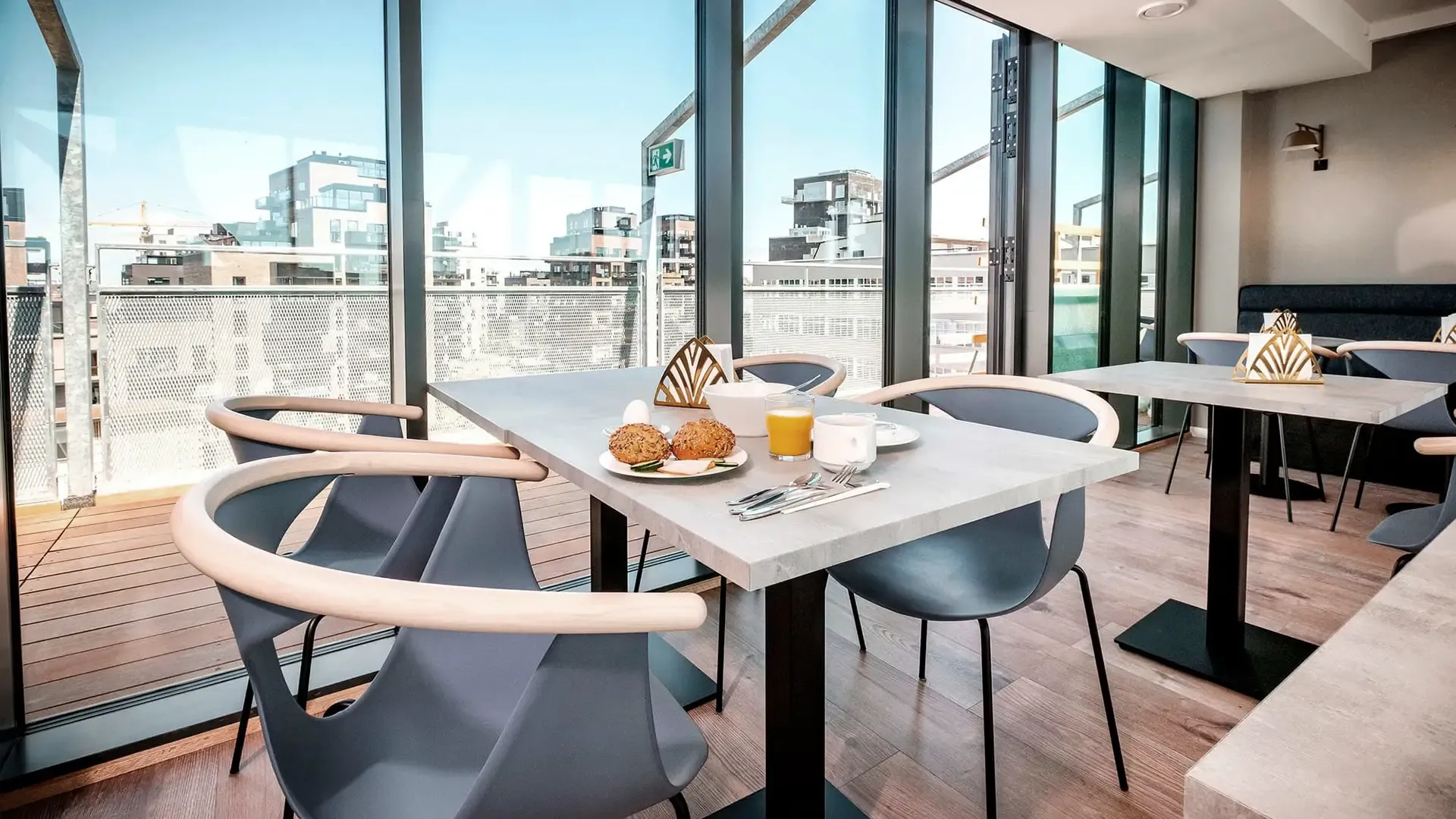 Breakfast table set with food in a hotel dining area with panoramic city view.