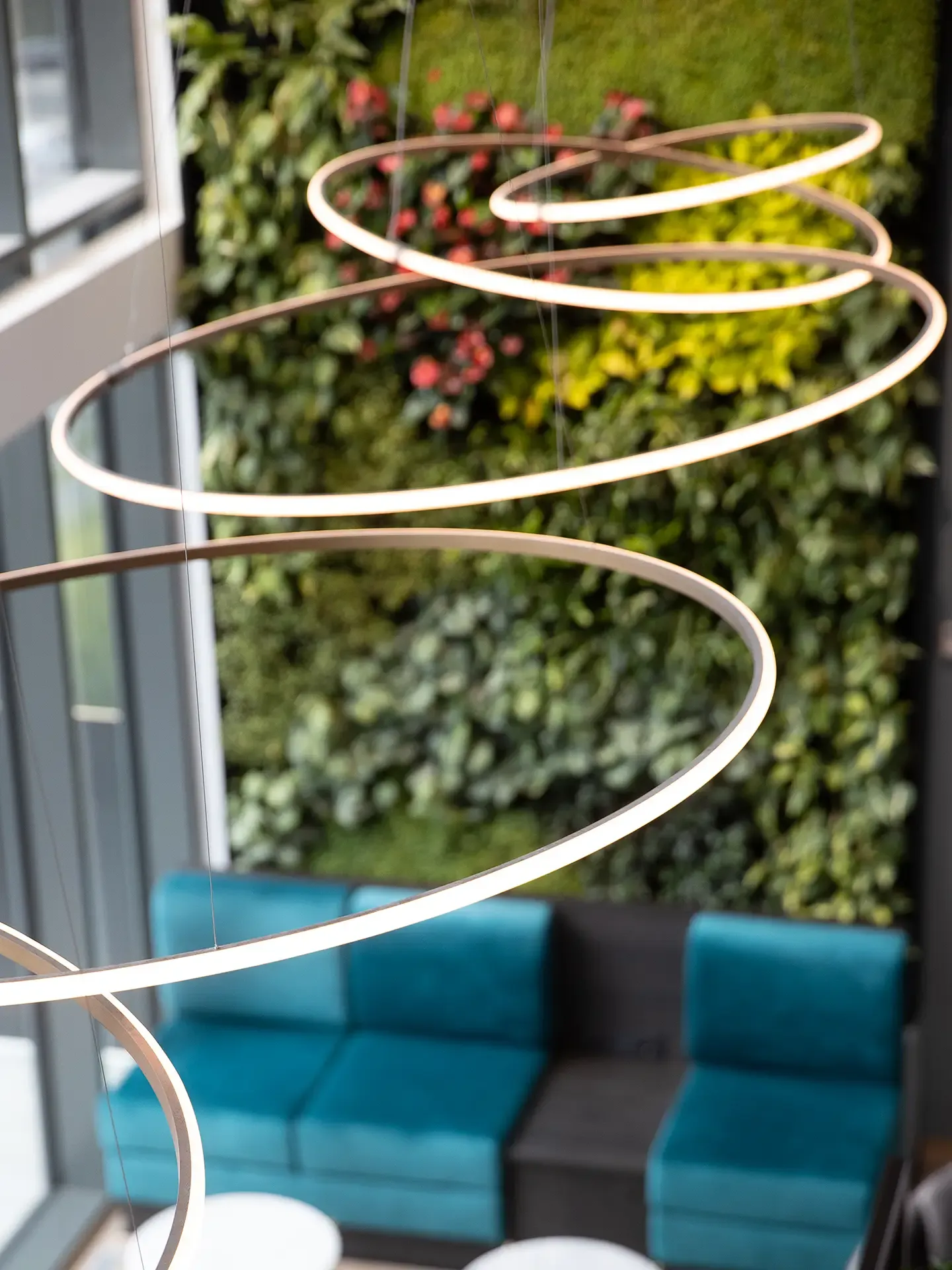 Green plant wall with decorative light installation in hotel lounge.