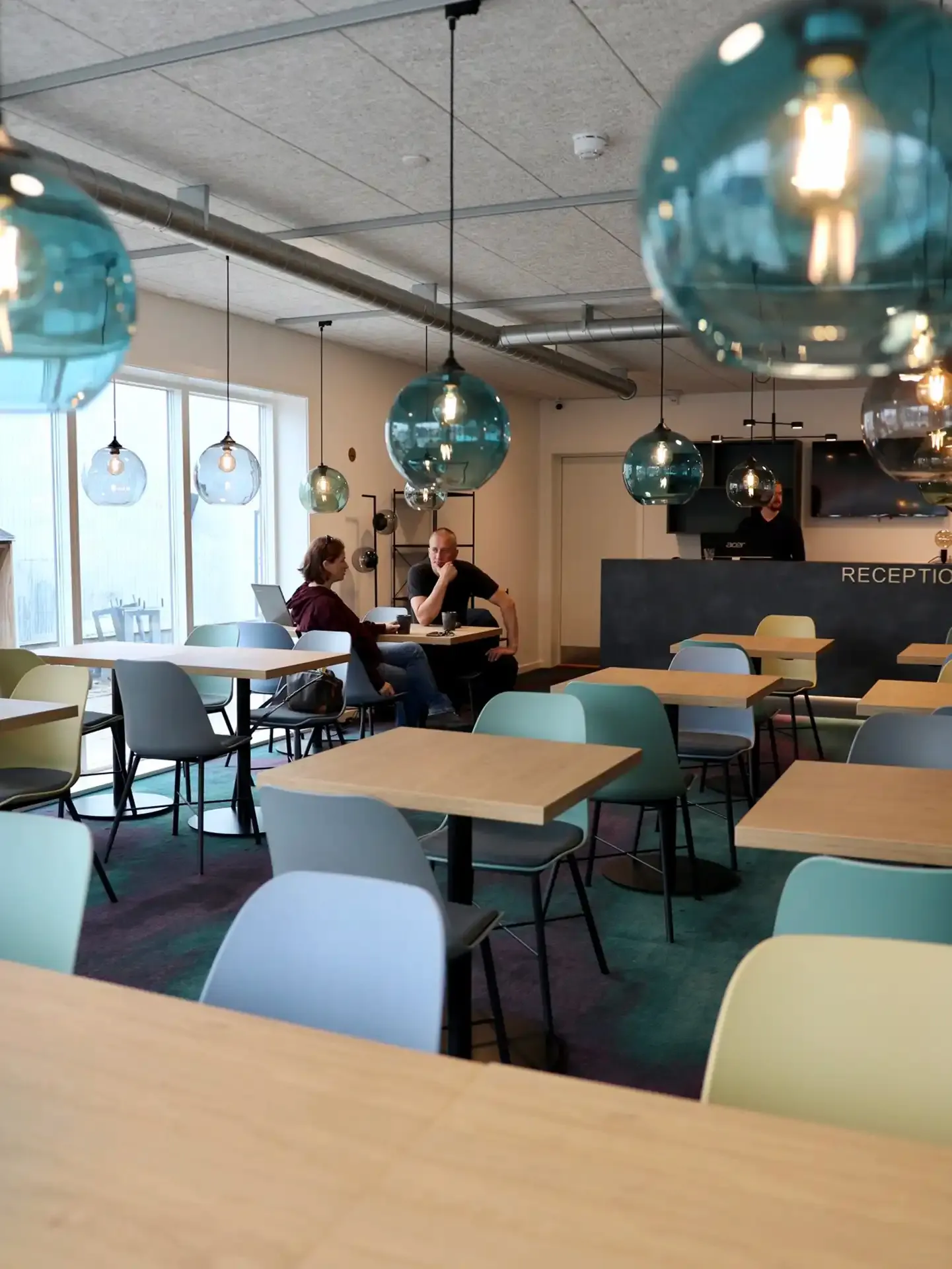 Flexible hotel lobby space with seating, pendant lamps and reception, designed by Third.space for multifunctional use