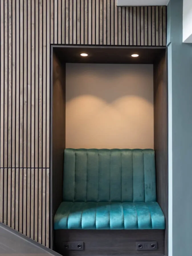 Built-in seating niche with blue banquette and wood panel walls in modern hotel lounge.