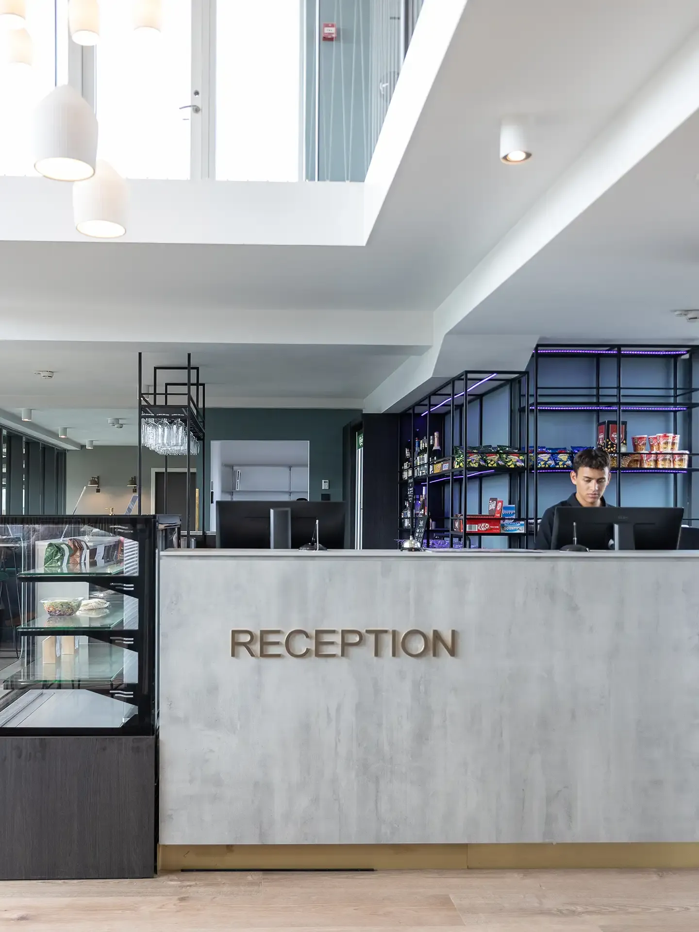 Reception counter with display shelves in contemporary hotel lobby.