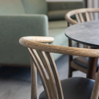 Hotel room dining table paired with green upholstered sofa. Homely feel and flexible interior.