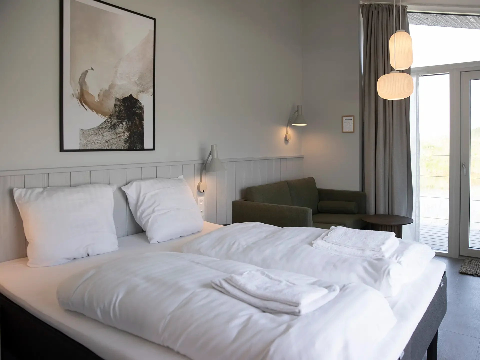 Hotel room with double bed and adjoining seating area. Relaxing interior design with calm colour palette