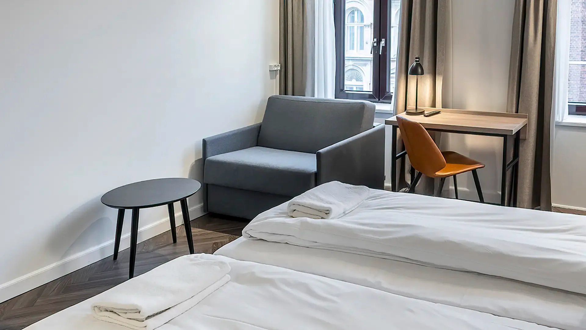 Compact hotel sleeping chair in grey fabric, designed for flexible guest accommodation.