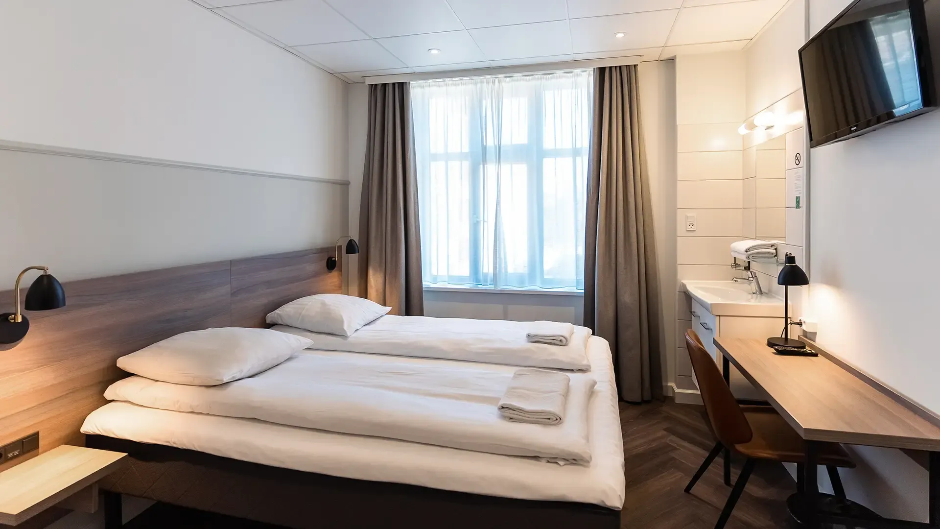 Hotel twin room with light wood headboard and minimalist Nordic styling — designed for contemporary hospitality comfort and timeless aesthetic appeal.