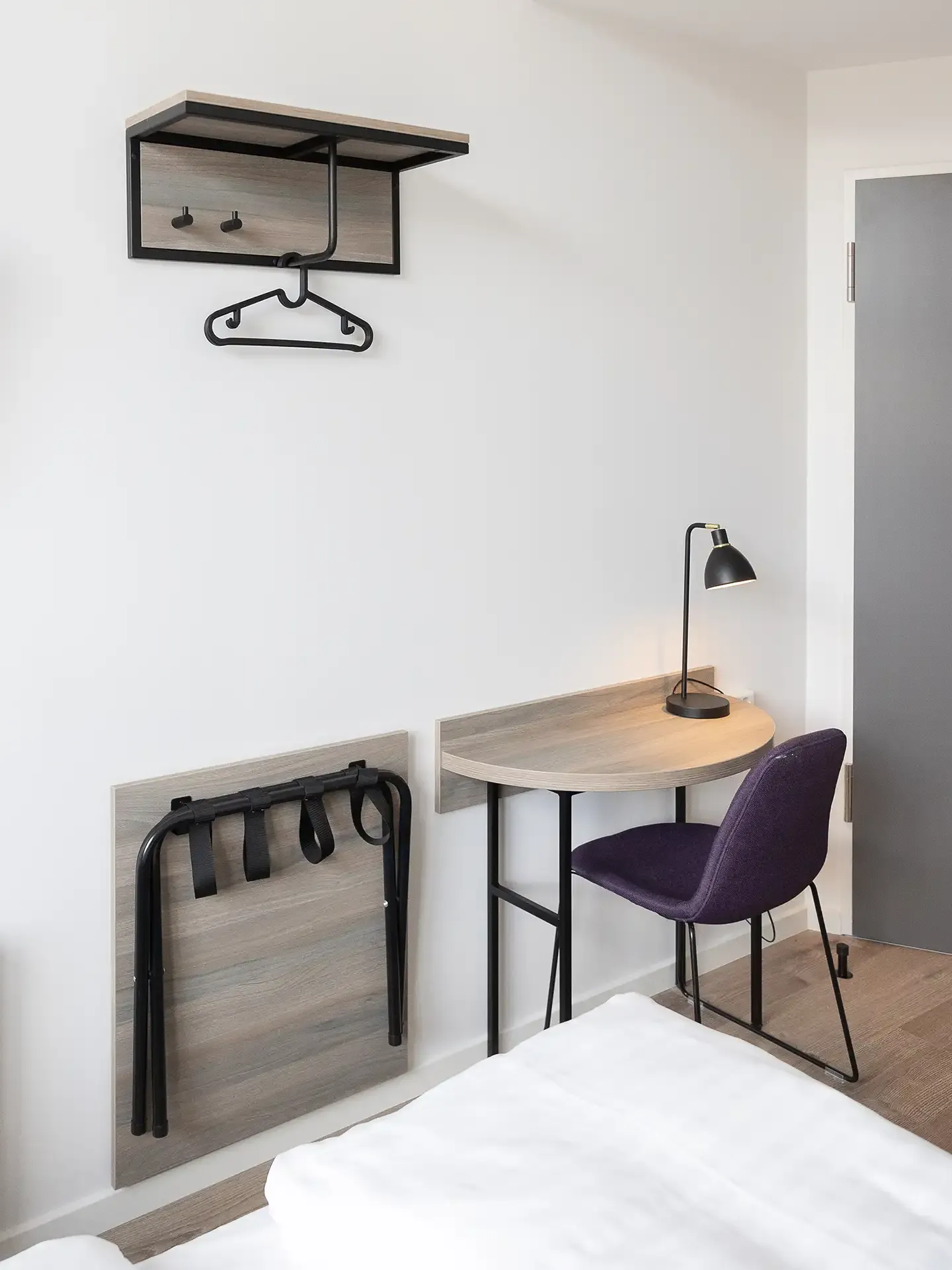 Hotel room workspace with desk, chair, and wall-mounted shelf. Nordic interior design.