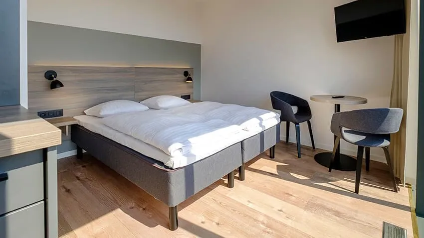 Hotel interior design by third.space. Nordic inspired design with soft-tone colours and wooden headboard.