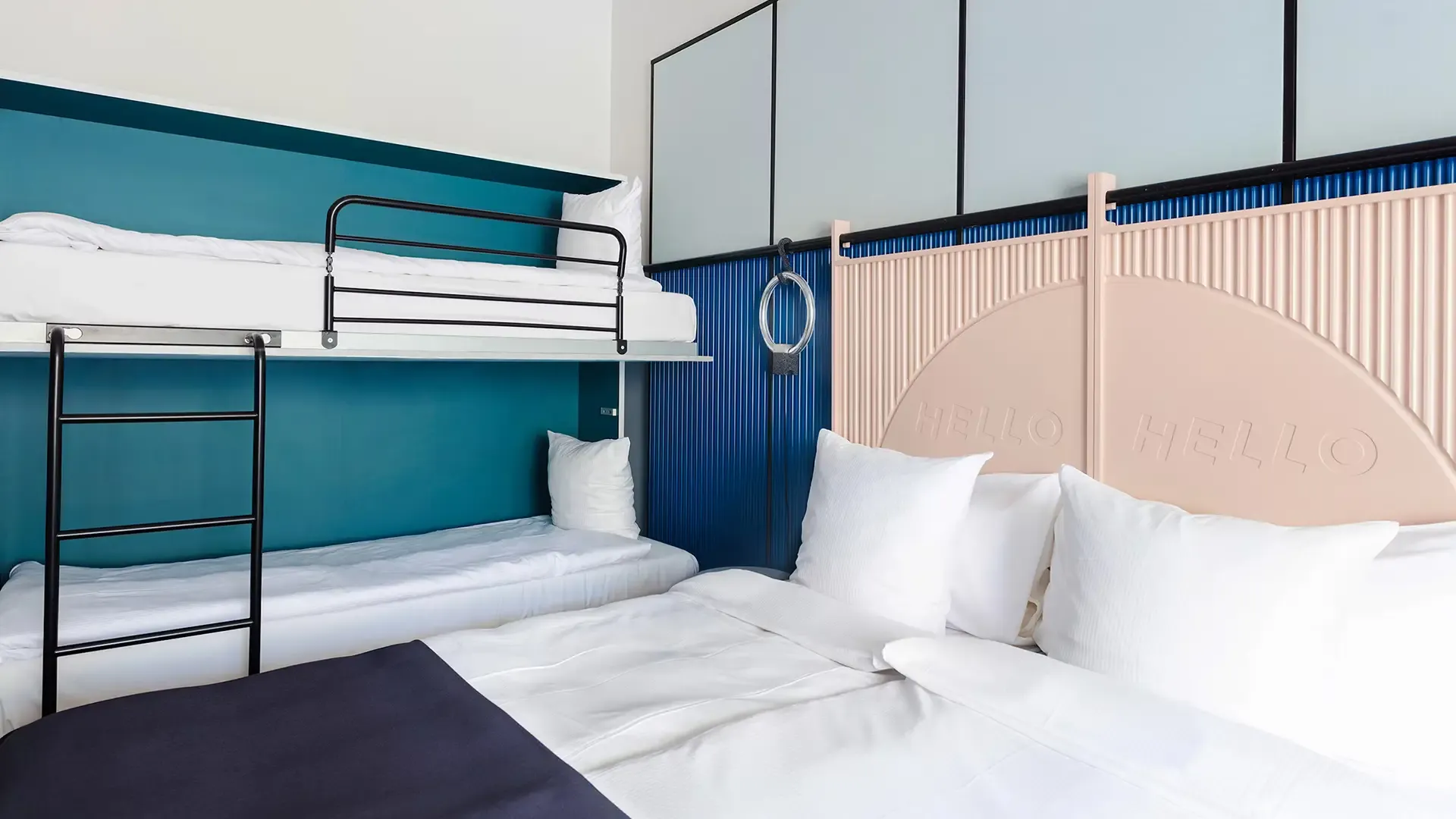 Modern hotel room with bunk bed and stylish blue wall panels