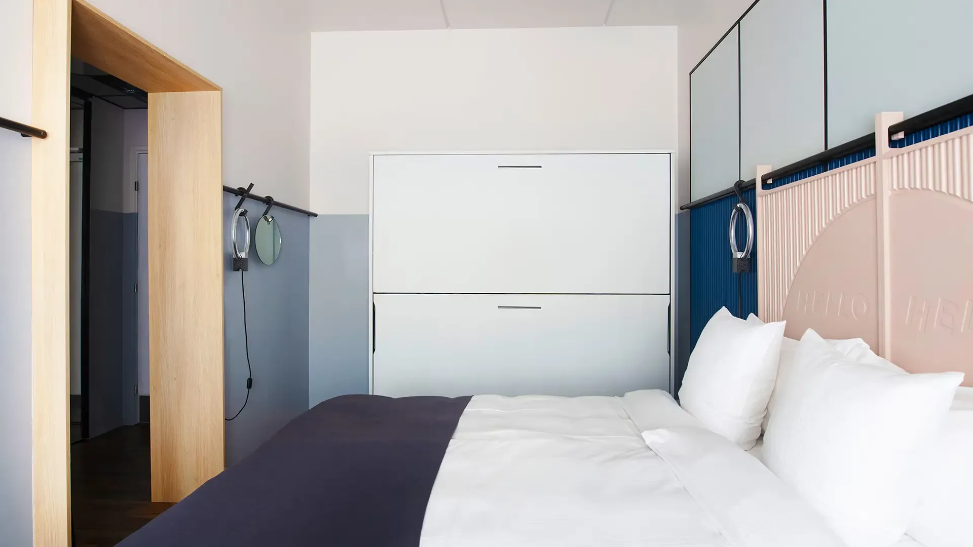 Modern hotel room with bunk bed and stylish blue wall panels. System folded up.