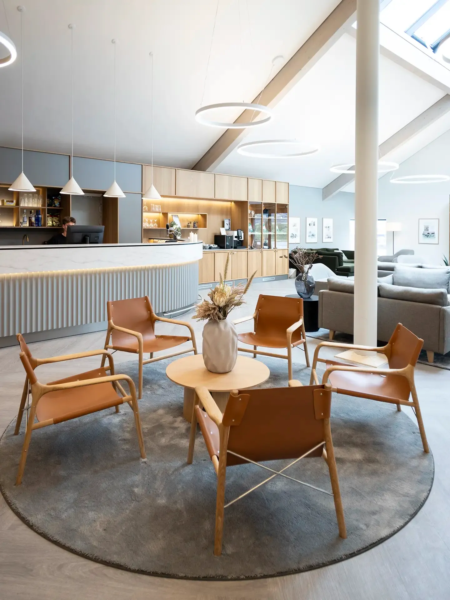 Hotel lounge with leather chairs and a round wooden table. Custome-made reception counter in elegant nordic design.