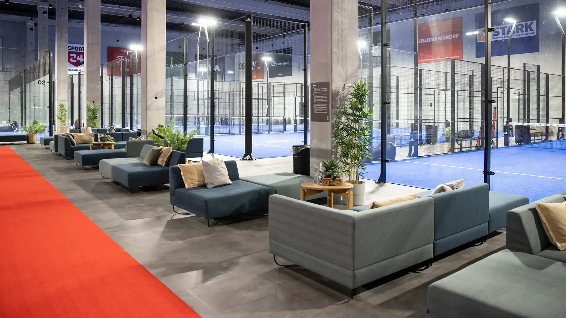 Spacious padel center corridor with lounge sofa groups, offering inviting zones for social interaction and post-match relaxation.