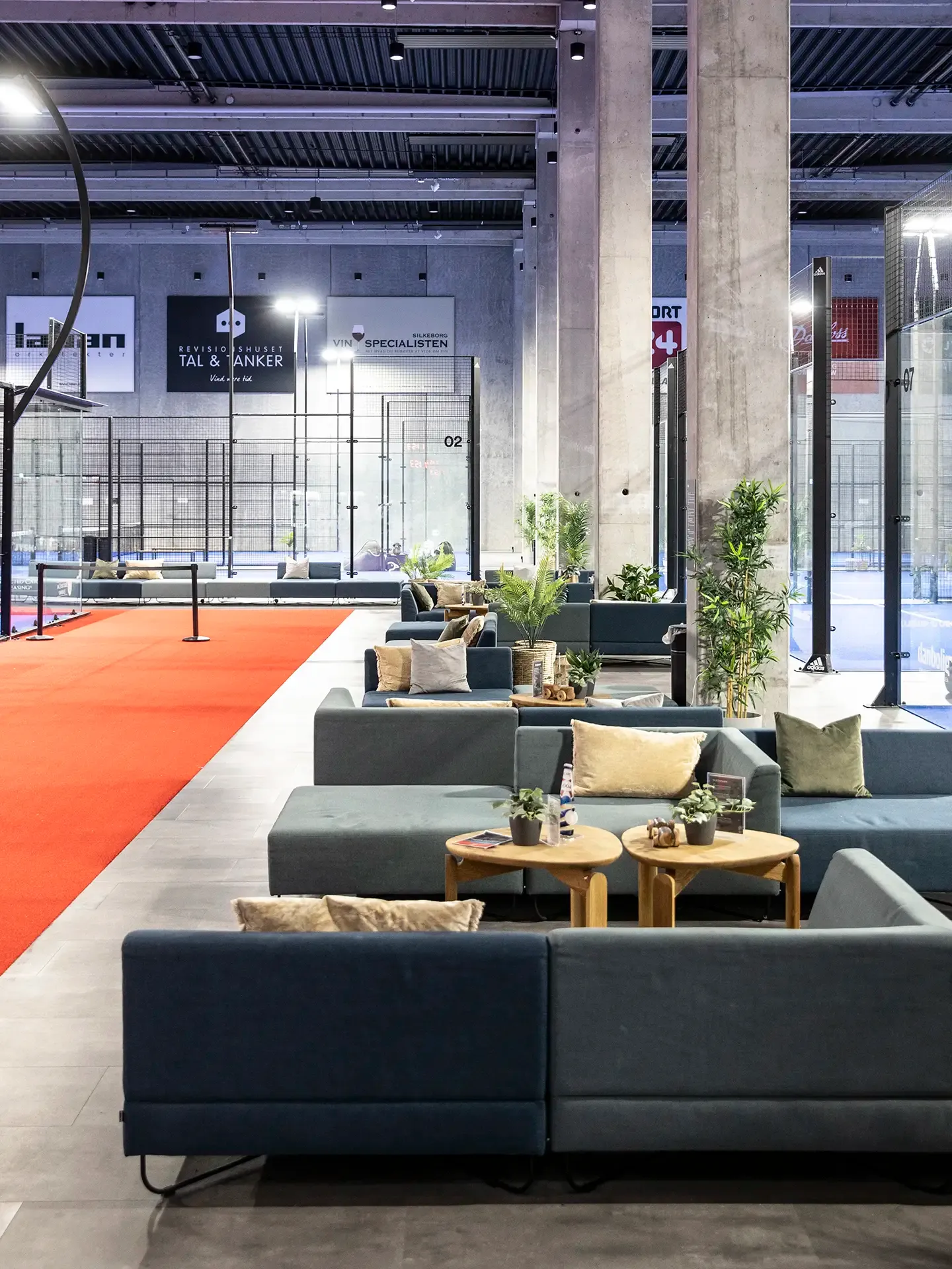 Lounge seating between padel courts, enhancing the user experience with easy access and comfort in an active setting.