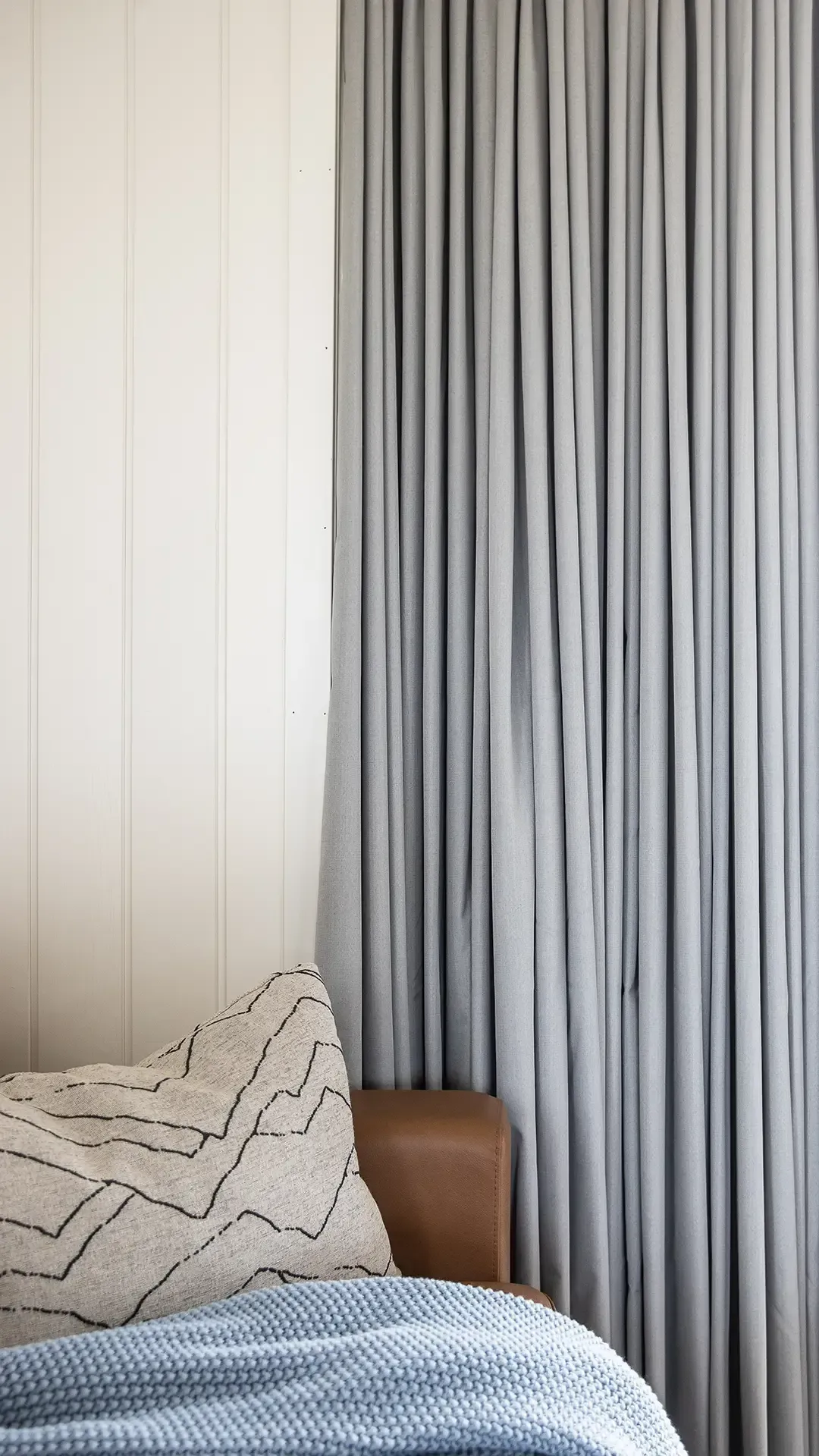 Nordic summer cottage materials: cognac leather, grey curtains, and blue light plug details