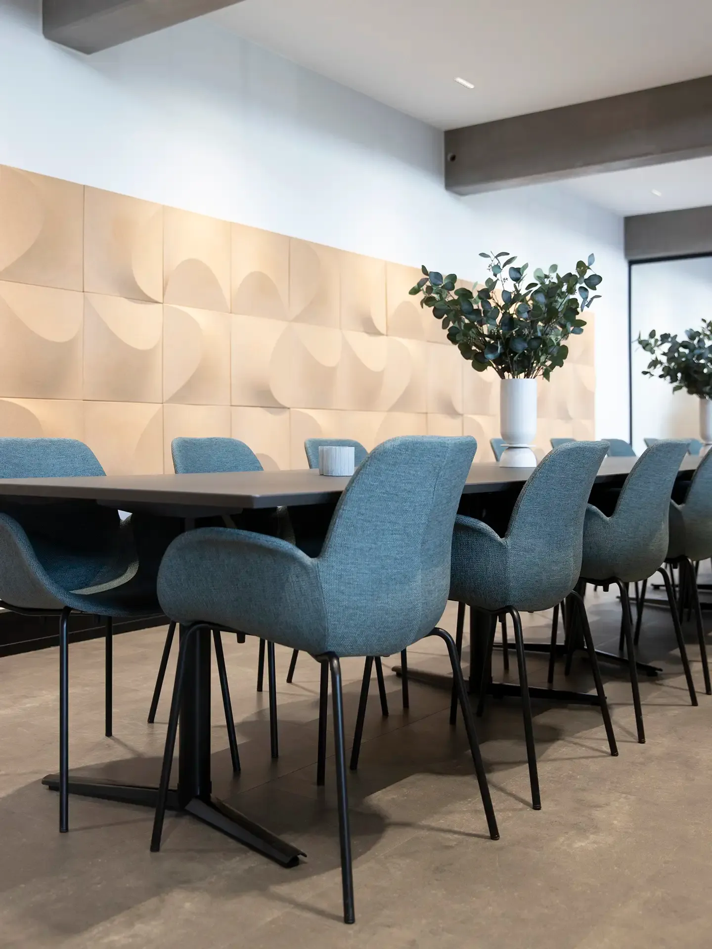 Meeting room with blue chairs and patterned cork acoustic panels for stylish sound absorption.