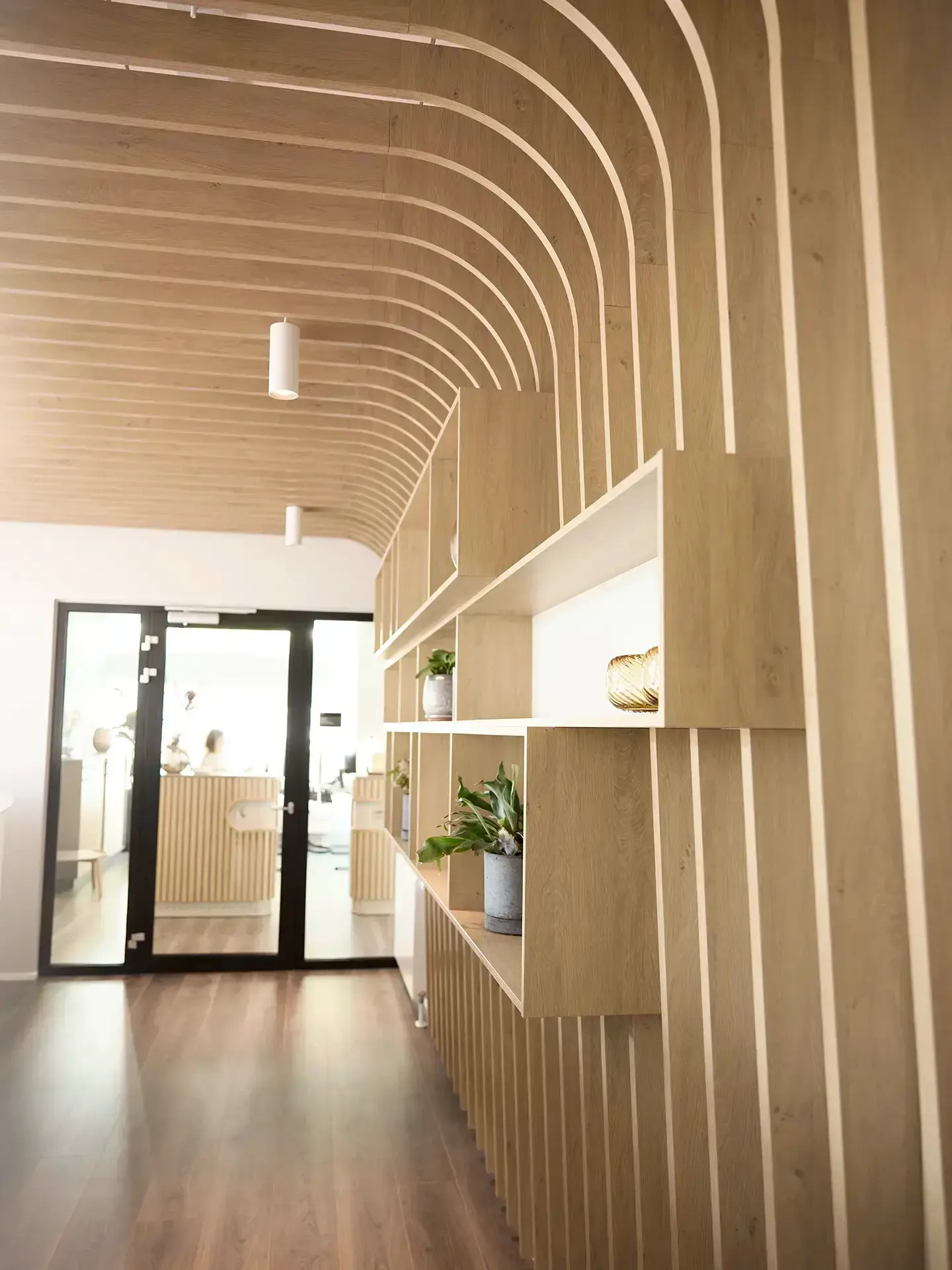 Workspace corridor featuring acoustic wooden ceiling panels and soft lighting — designed for wellbeing and productivity in modern office interiors.