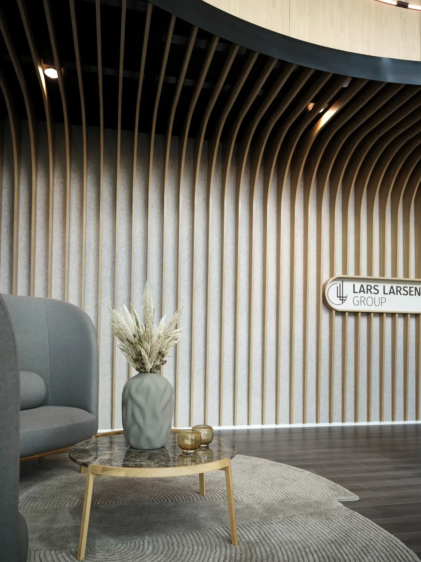 Contemporary office entrance with wooden slat wall and Bolia furniture at Lars Larsen Group head office.
