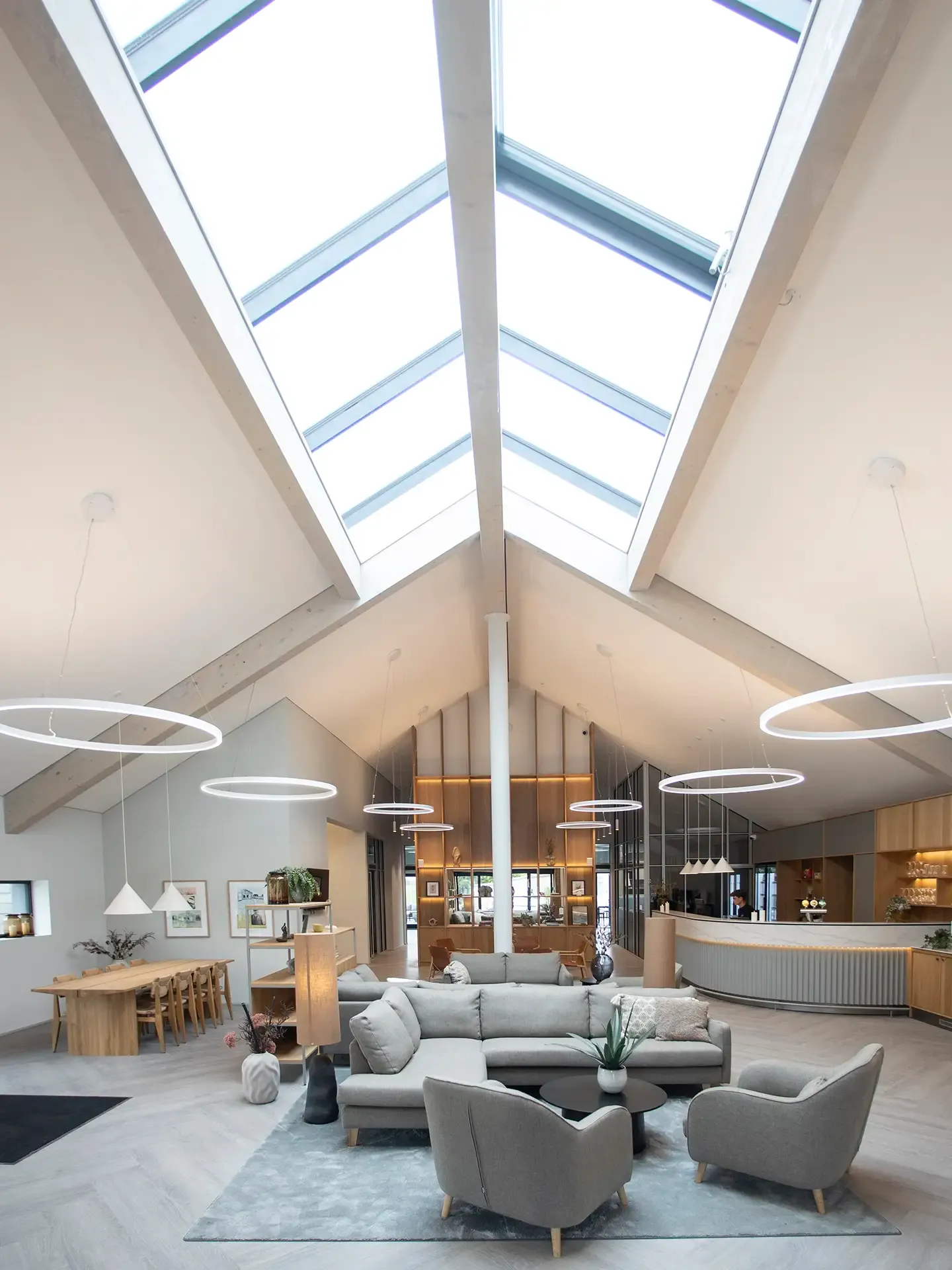 Reception design for modern hotel public spaces. Lounge areas, high ceiling and roof windows.