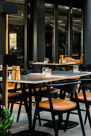 Exclusive restaurant design with black dining chairs with cognac seating and black columns