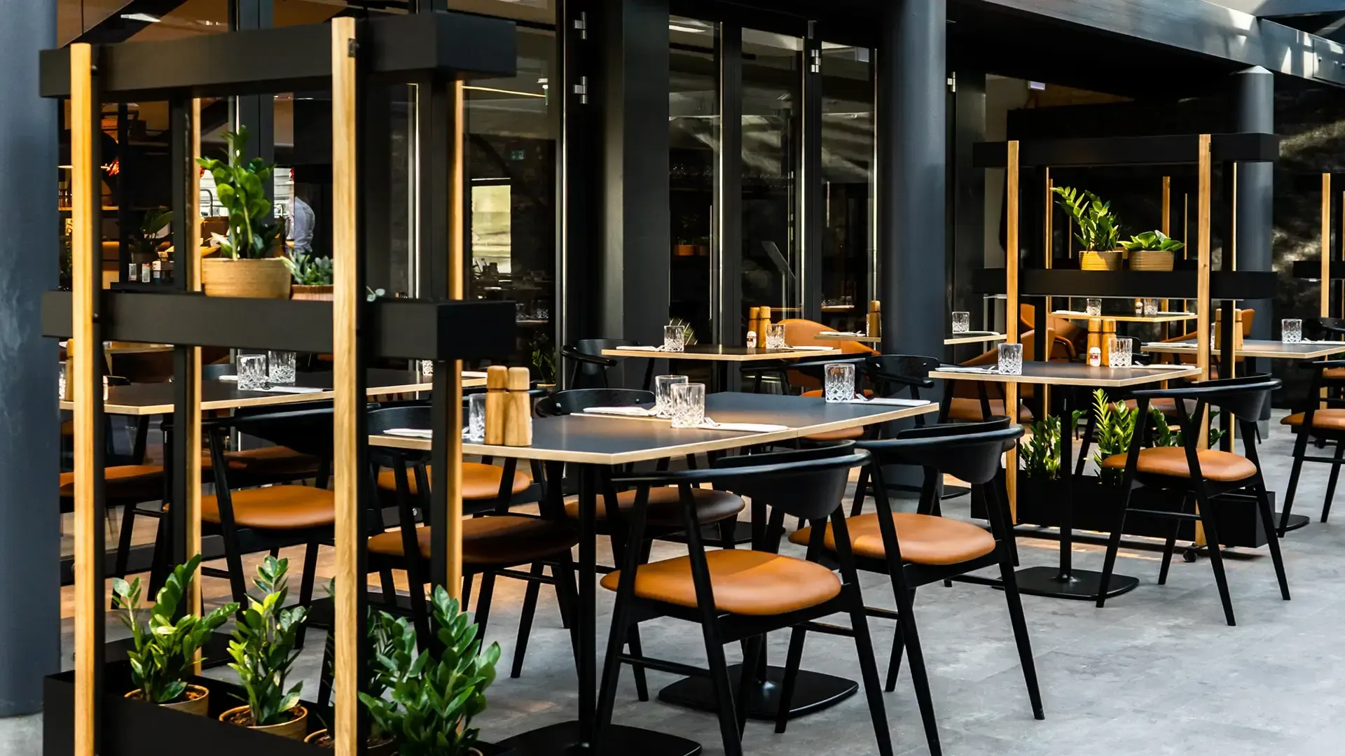 Exclusive restaurant design with black dining chairs with cognac seating and black columns