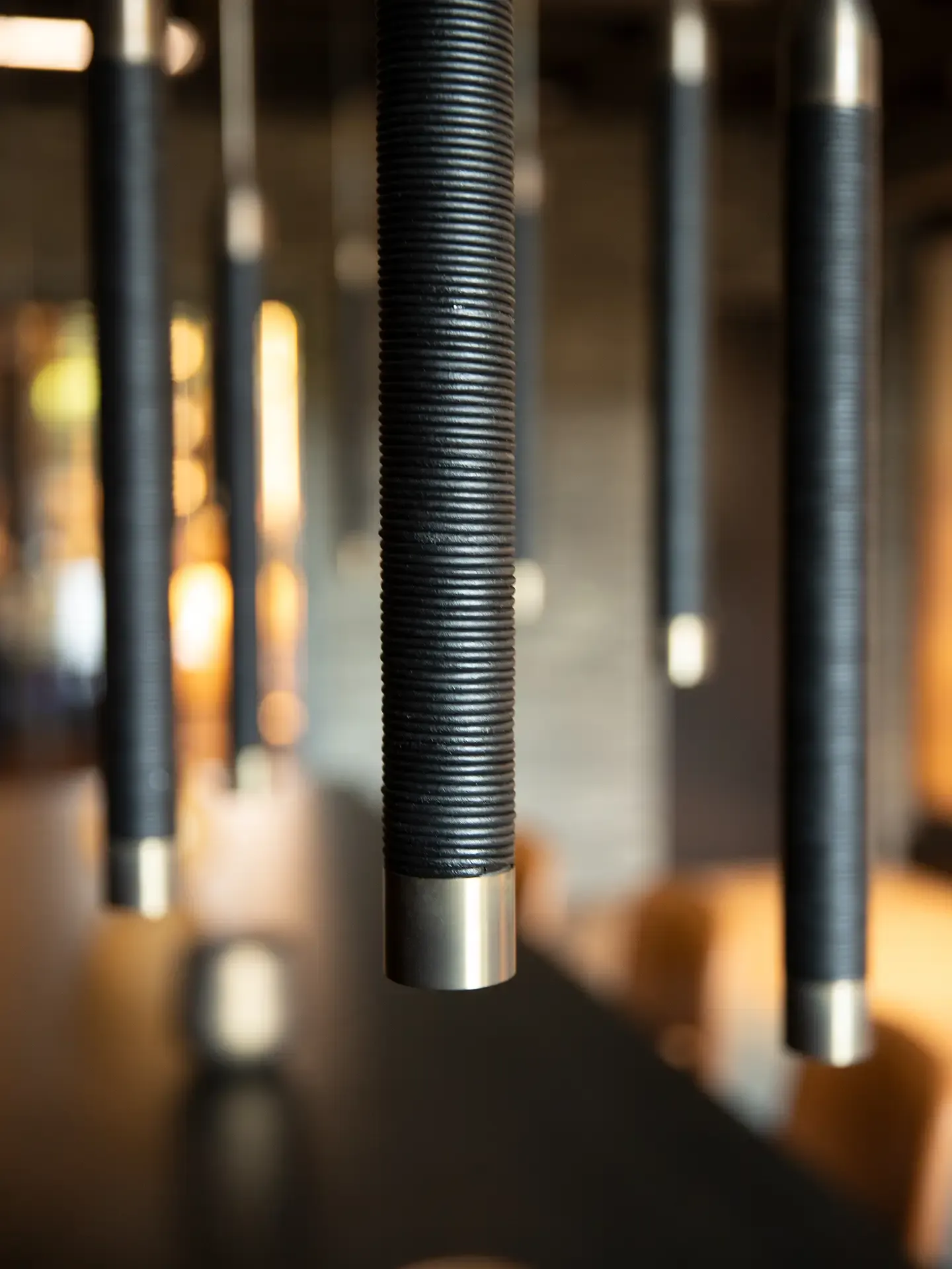 Close-up of brass One A pendant lights against dark ceiling in modern showroom interior.