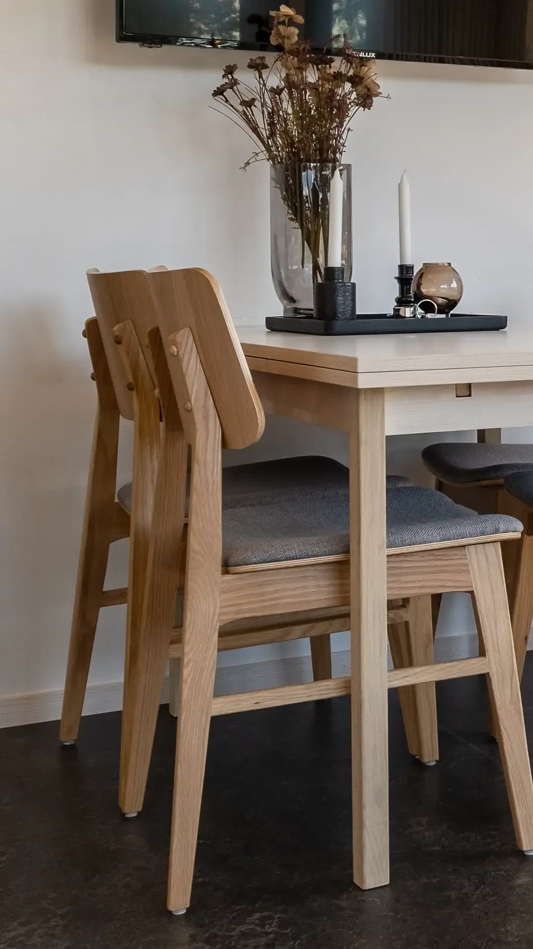 Close-up of oak dining chair with grey cushion, part of Scandinavian dining set in compact cabin – crafted for comfort and modern Nordic design.