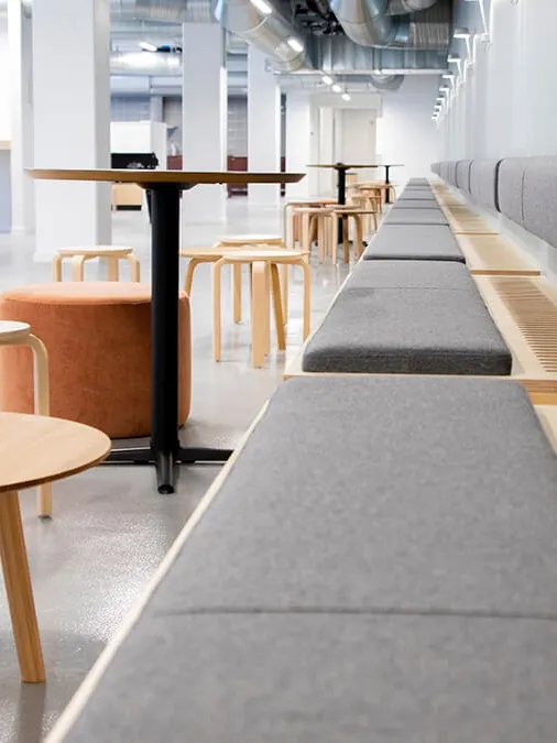 Custom café-style interior with built-in bench seating and wooden tables, designed for modern student housing at Telegrafkollegiet.