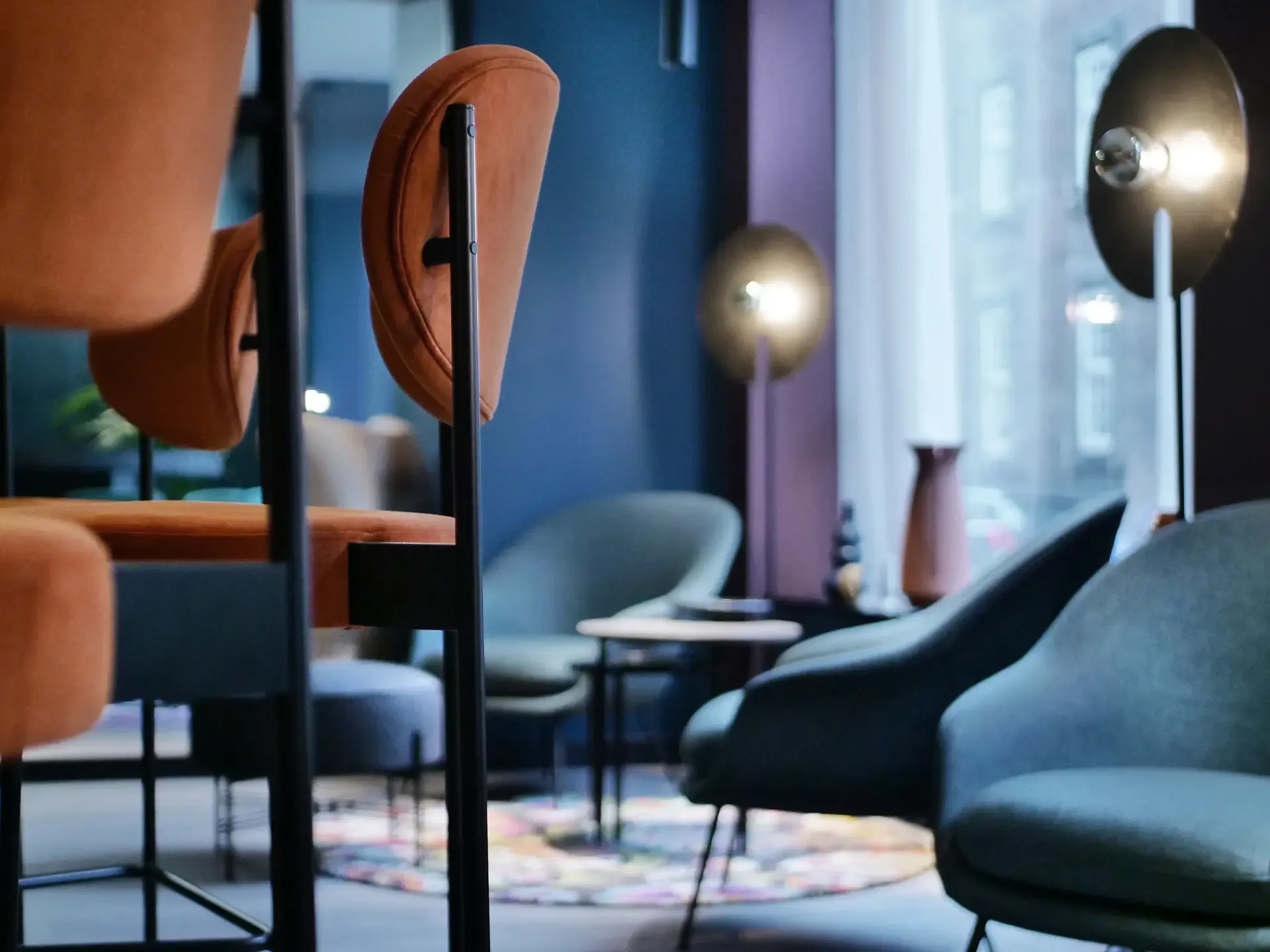Hotel-lounge seating in deep earth tones with curated lighting and dark contrasts.