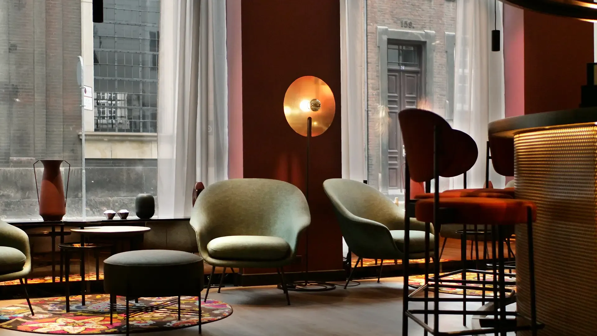 Cozy seating area with soft green chairs, sculptural lighting and views to the street.