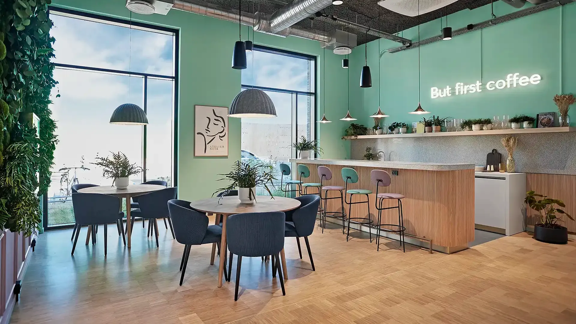 Student living cafe area with plant wall and cool neon sign on modern green wall