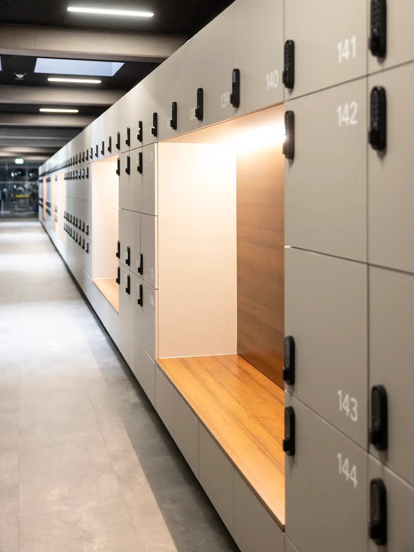 Long hallway with custom locker wall and integrated wooden bench, suitable for high-traffic training centers or health clinics.