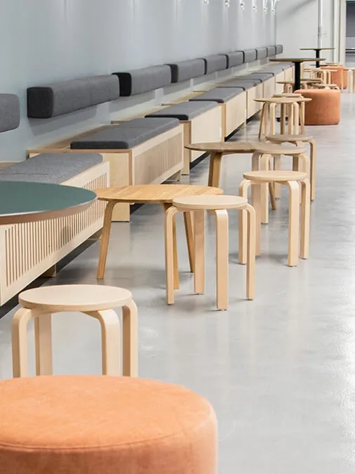 Custom long bench seating with integrated small side tables, designed for modern student living interiors.