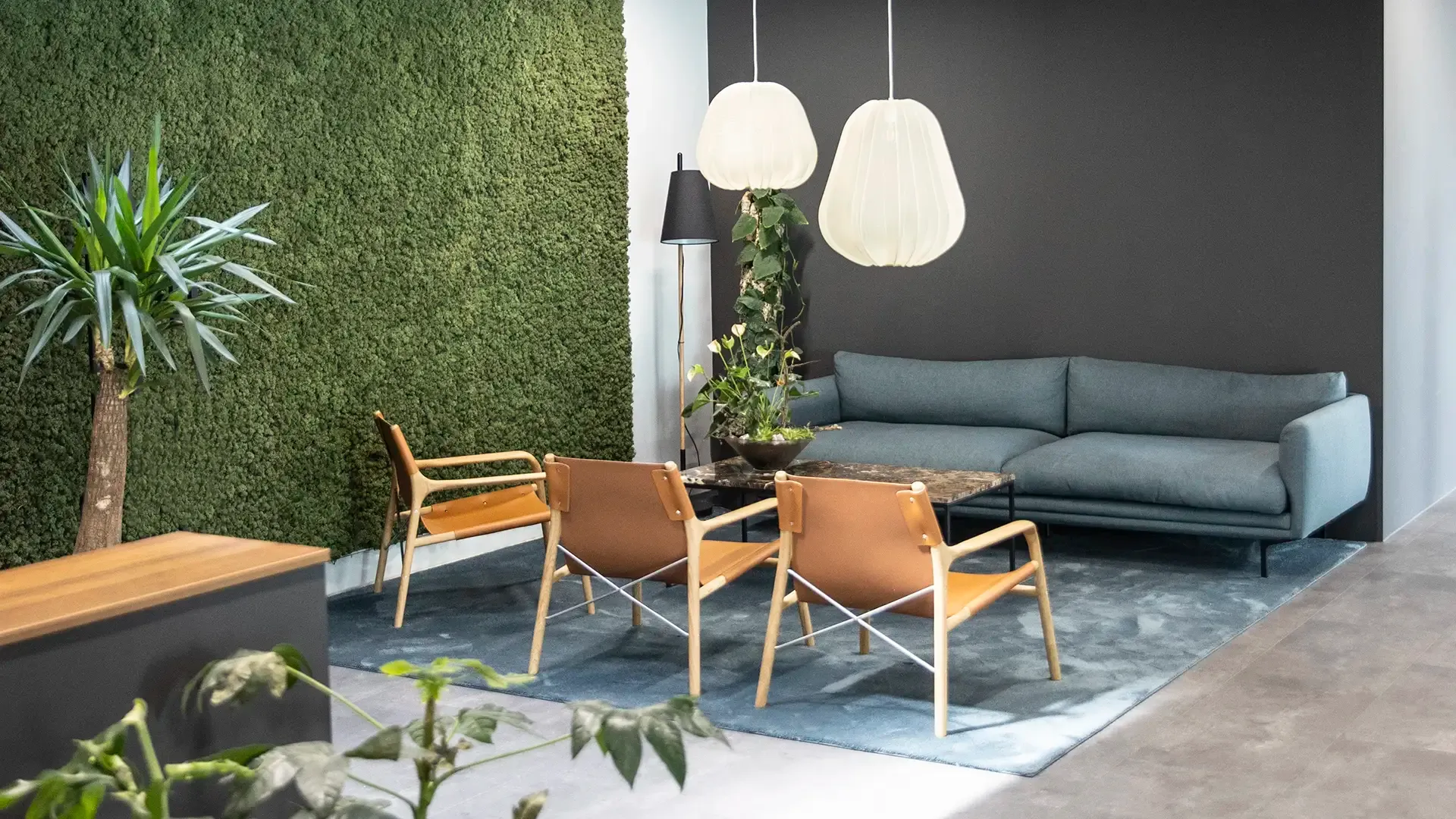 Custom clinic lounge area featuring green moss wall, pendant lighting and curated furniture for a biophilic, soothing environment.