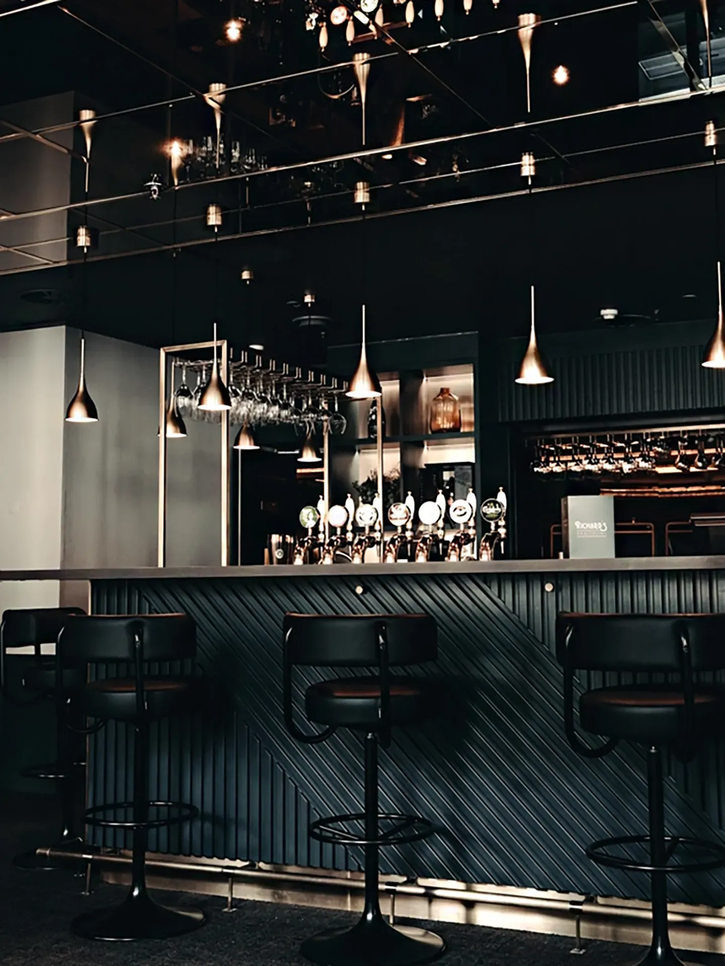 Custom-made bar counter with spectacular herringbone pattern in dark colours. Bar with an intimate and luxurious atmosphere.