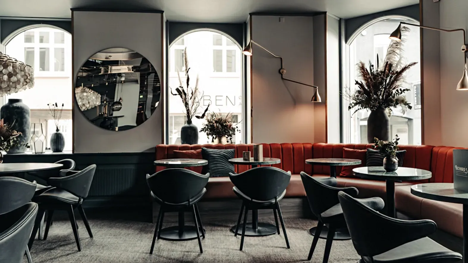 Dining space with velvet seating and elegant round tables in a bespoke restaurant design at Richards Bar.