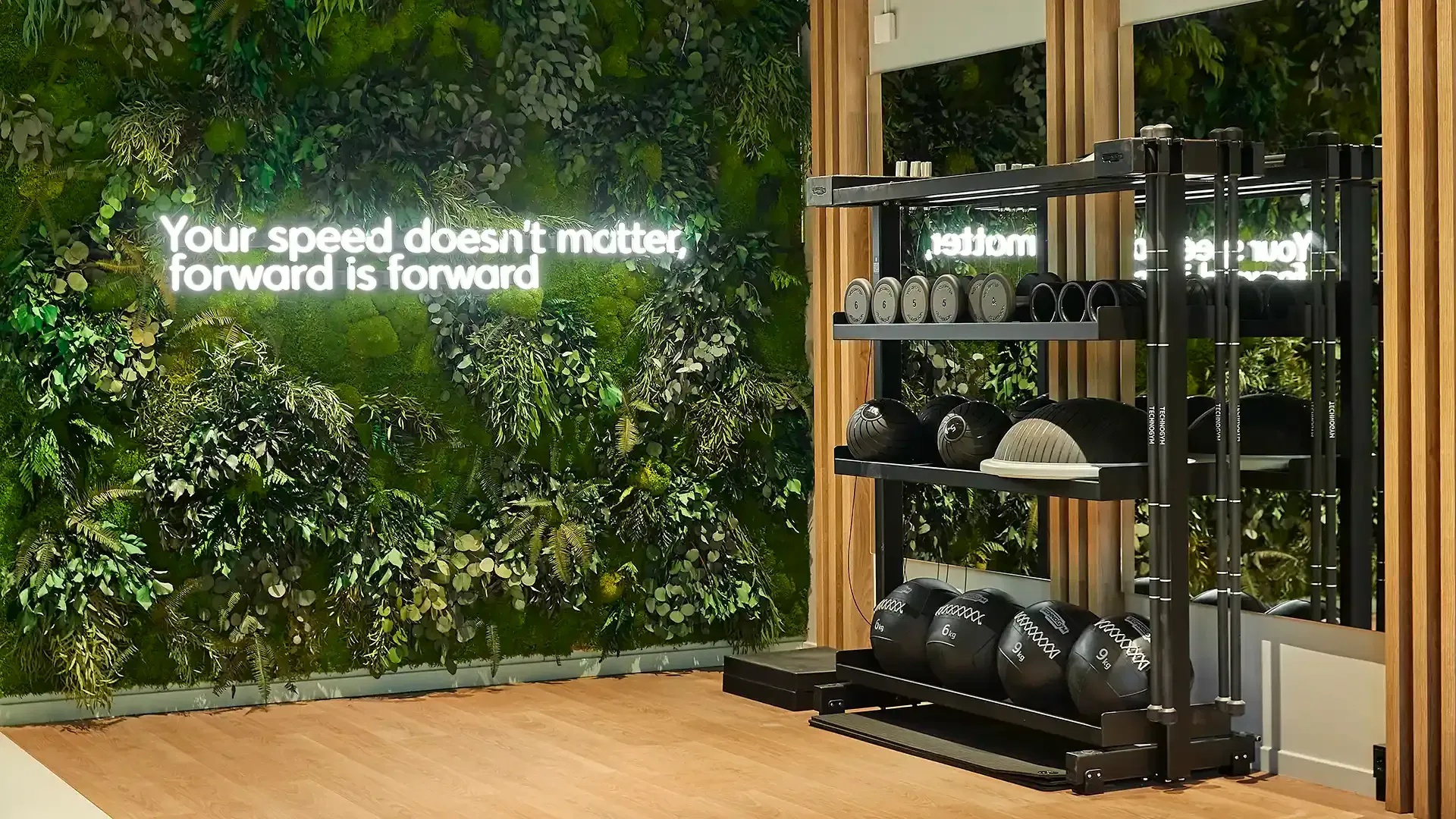 Fitness area at co-living housing with neon sign and plant wall