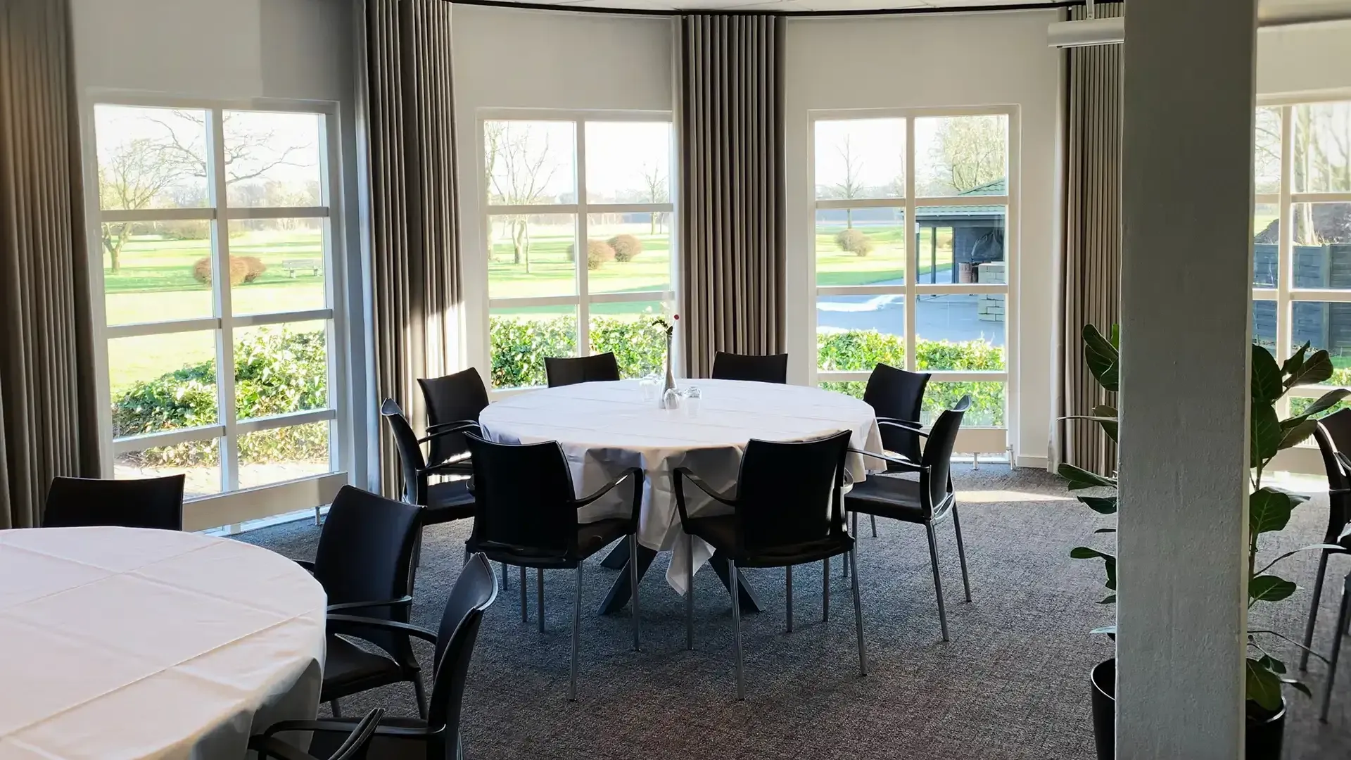 Dining room at golf venue with large windows and round tables