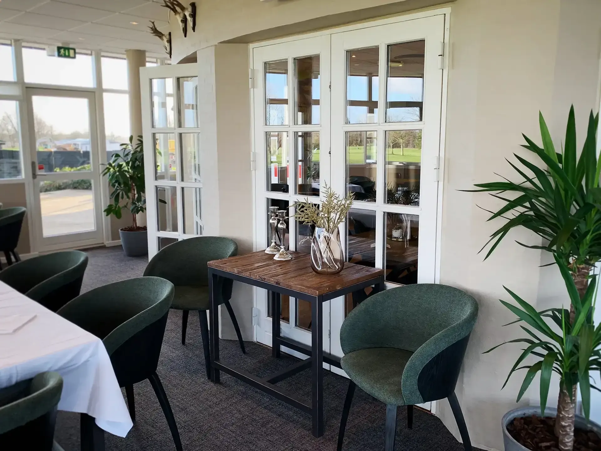 Golf club dining room with green chairs and natural lighting