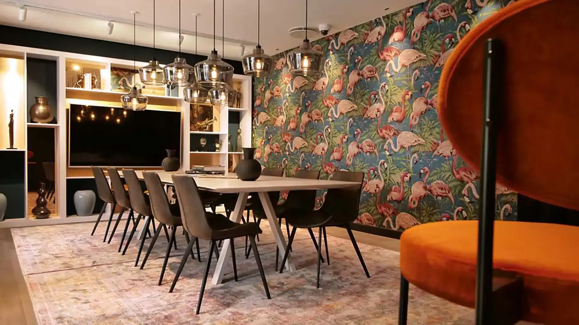 Meeting room with flamingo wallpaper, glass pendants and custom shelving – bold and personal take on business interior at hotel.