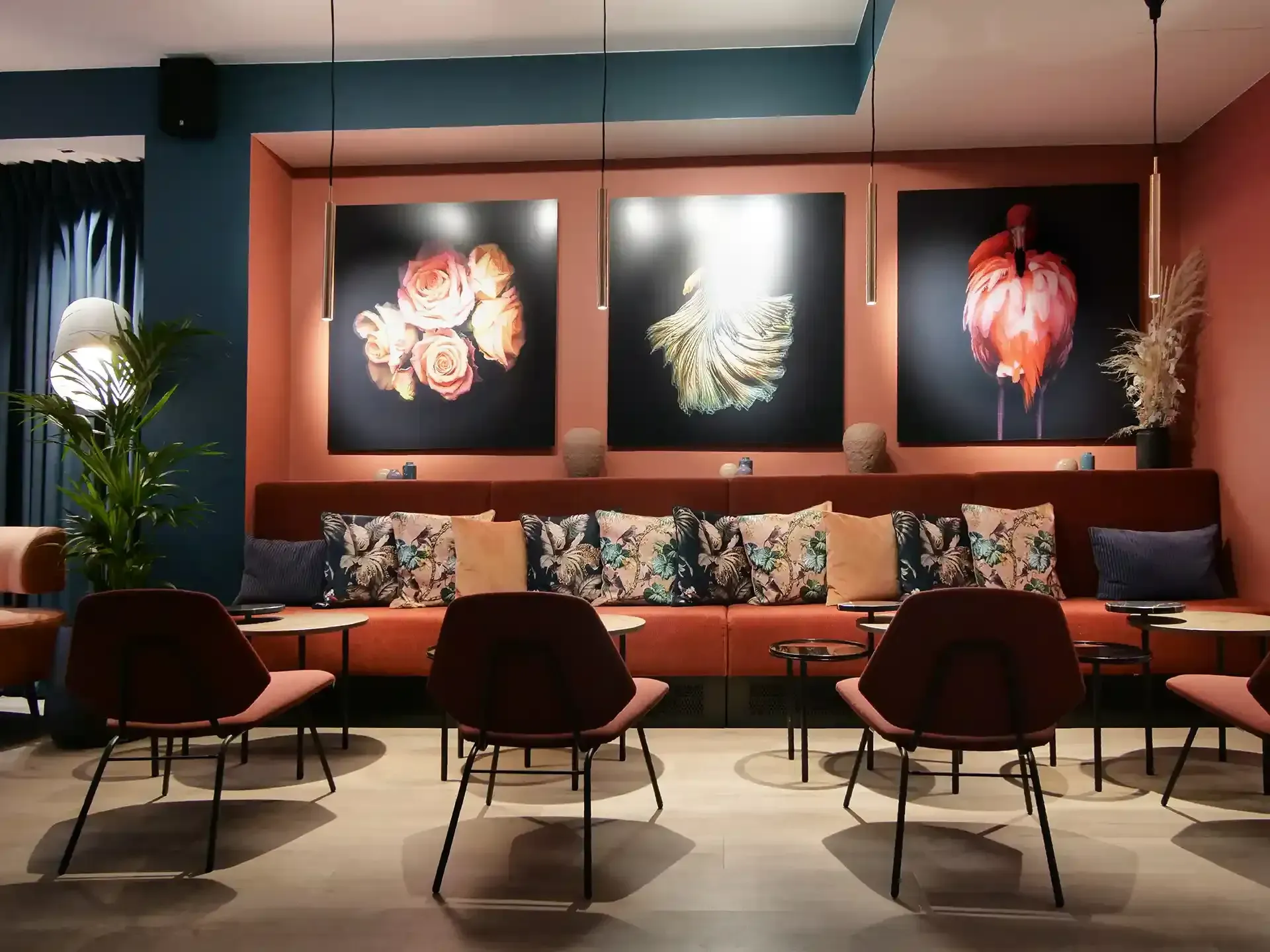 Hotel lounge with floral artwork, terracotta walls and velvet textures – a vibrant and expressive hospitality setting.