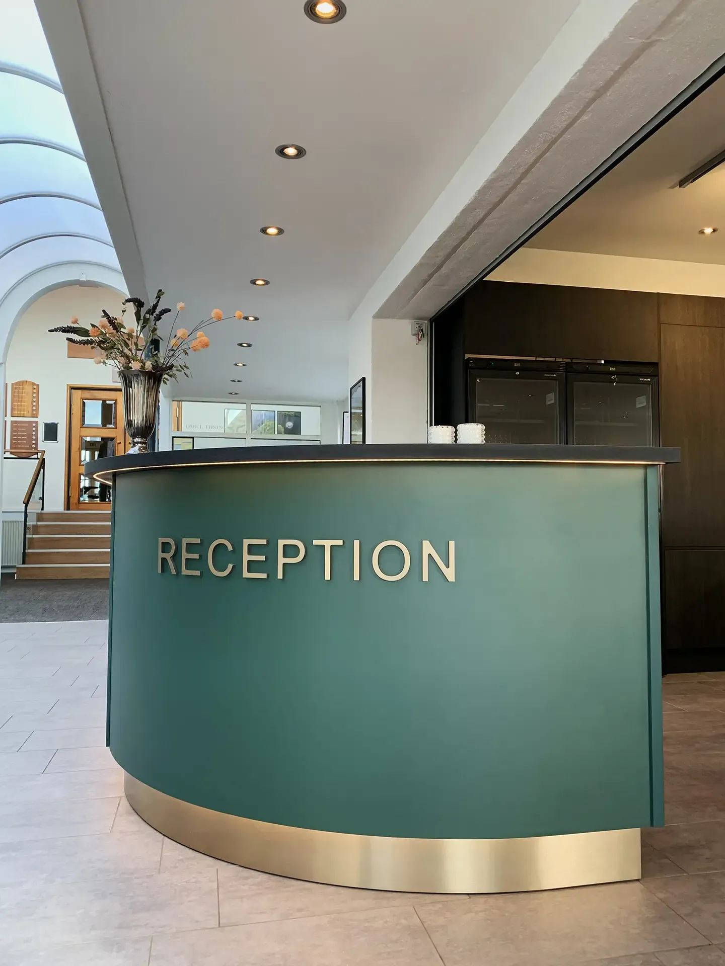 Custom made green reception desk with brass base and soft curves