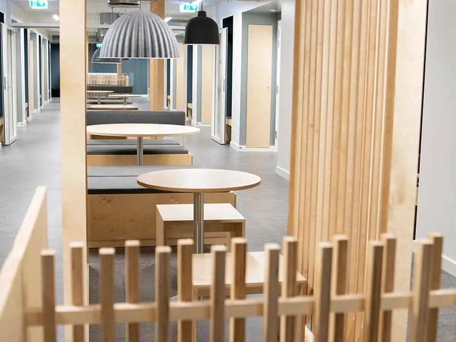 Lounge seating with oak wooden partitions and acoustic lighting, enhancing privacy and comfort in student living environments at Telegrafkollegiet.